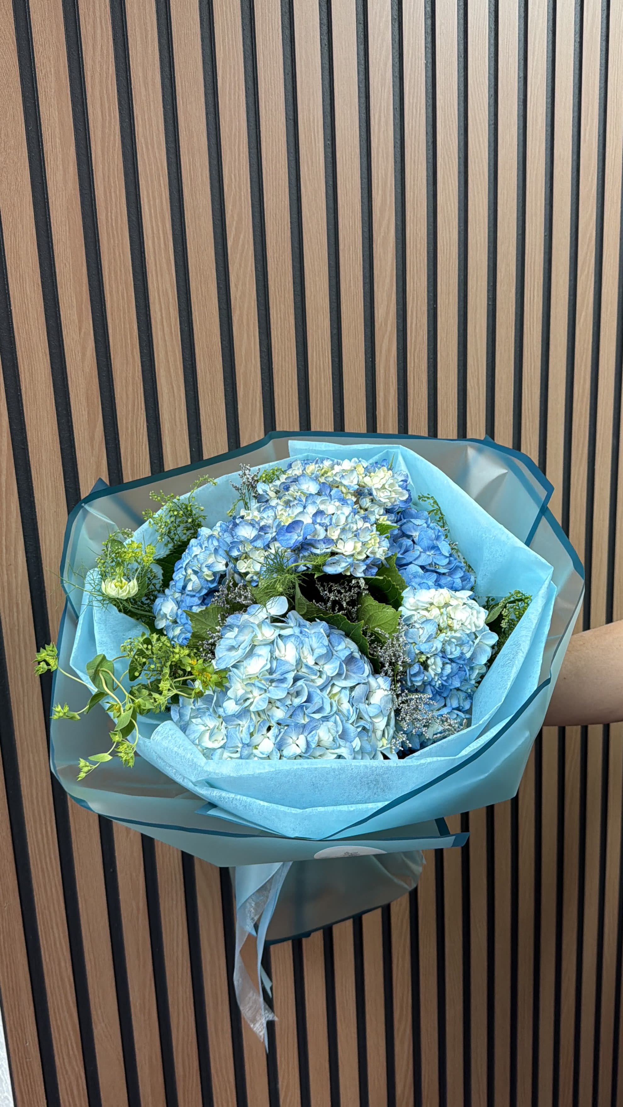 Blue hydrangea bouquet wrapped in turquoise paper
