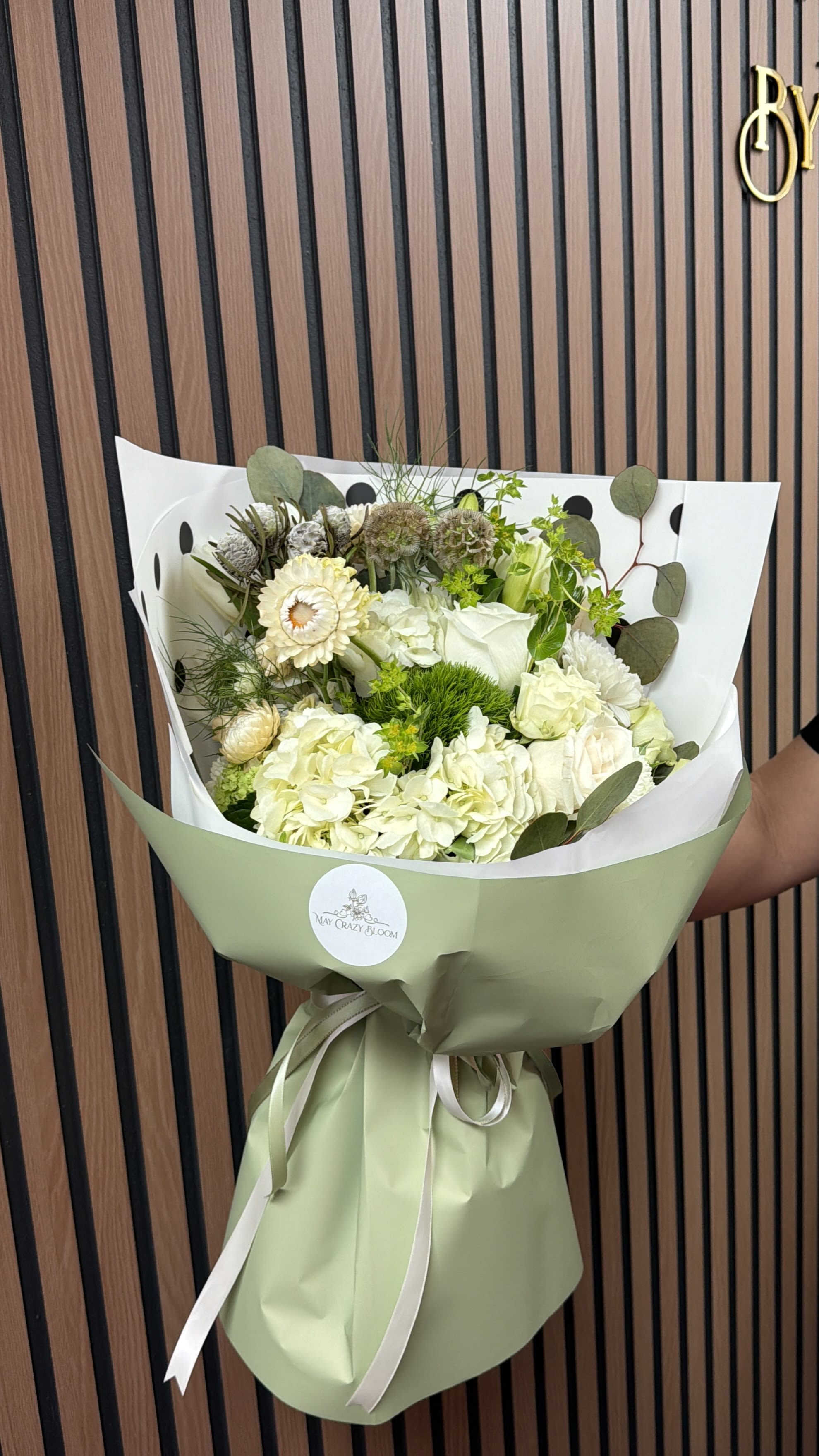 Bouquet of white and pale green flowers wrapped in green paper