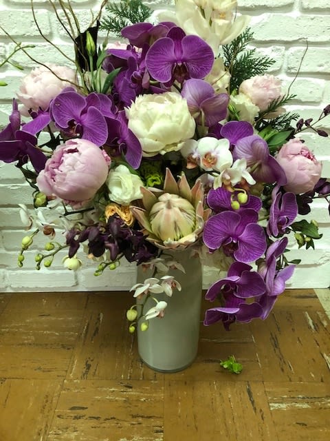 Purple orchids and pale peonies arranged in a tall vase