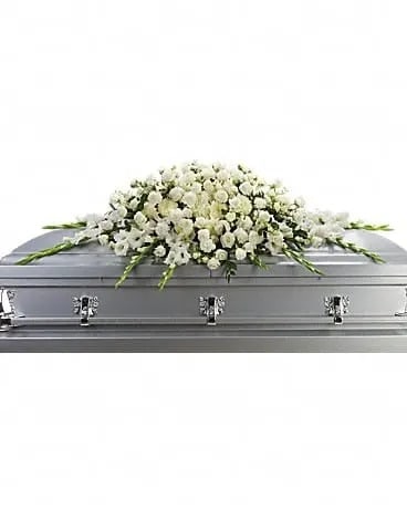 Love's Purity - A blanket of snow-white flowers gracefully placed on the casket is a lovely and very personal way to say goodbye to a loved one. It is a reminder of family devotion and unity at a time when it is needed most. This exquisite casket spray includes white roses, white spray roses, white gladioli, white carnations, white larkspur and white chrysanthemums accented with fresh greenery. 