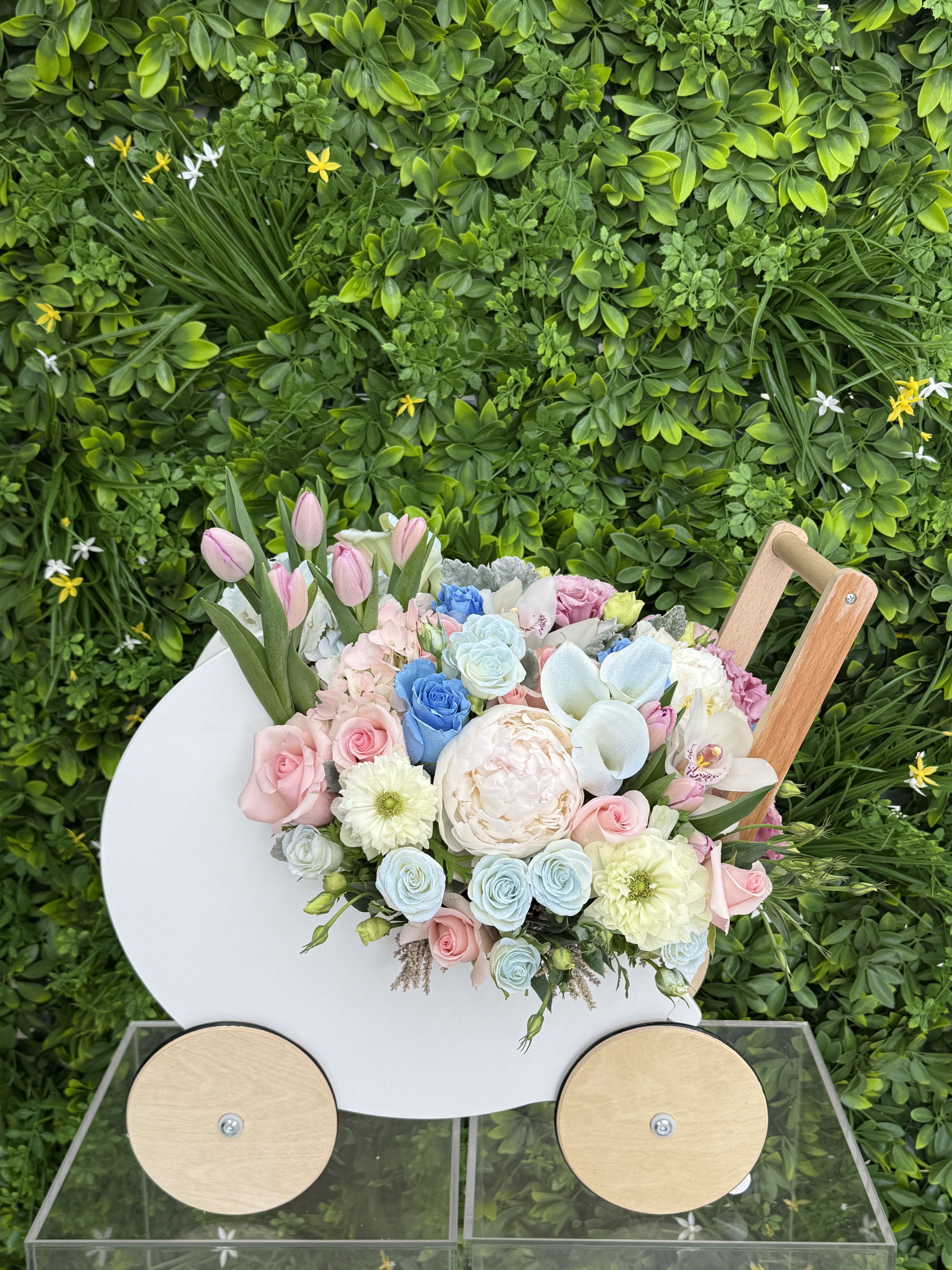 Pastel bouquet of roses, tulips, and peonies in a white cart