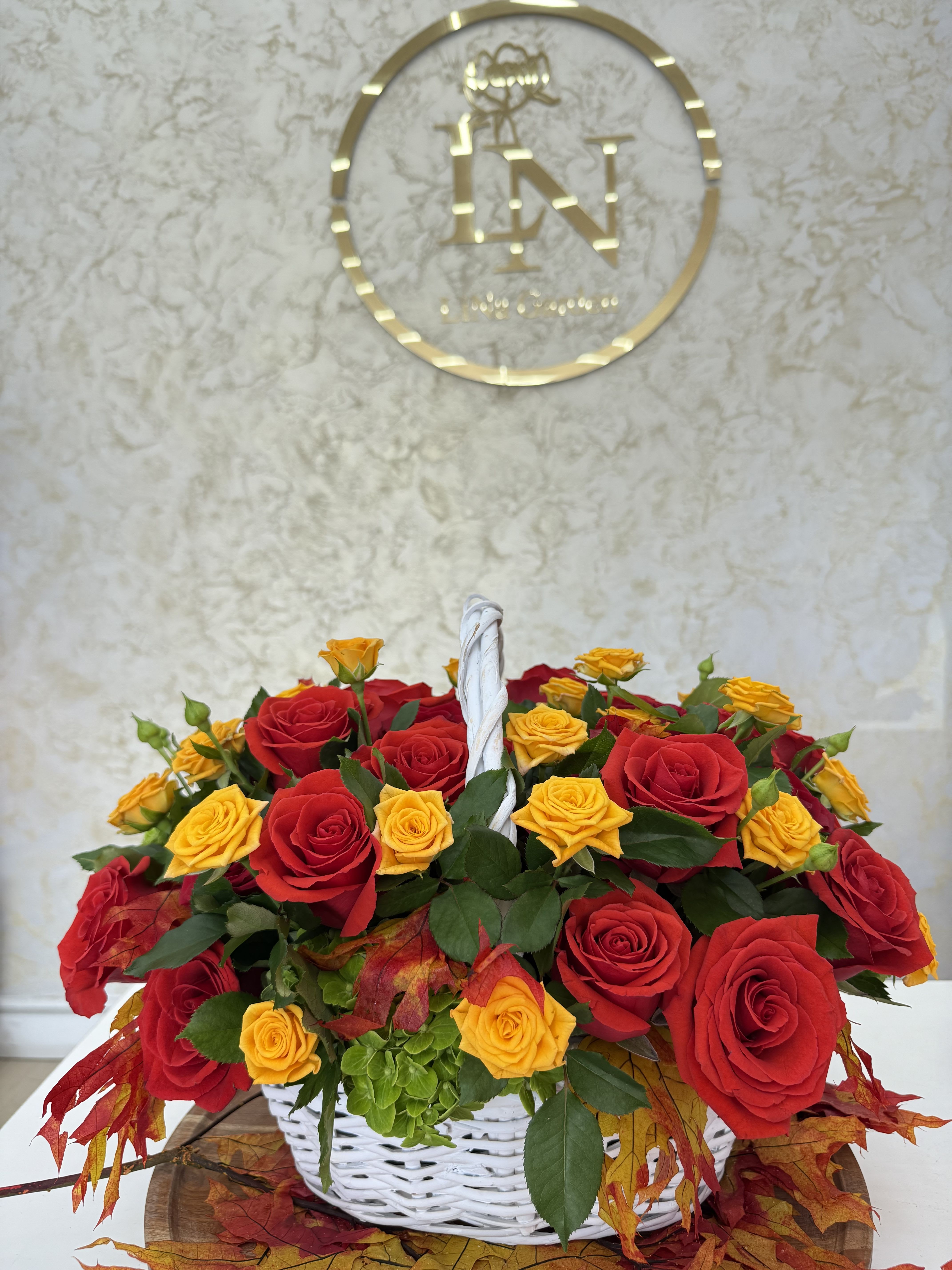 Basket of red and yellow roses with autumn leaves