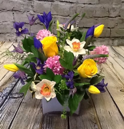 Bright Spring Day - Nestled in a sleek modern white container, this compact yet full arrangement is perfect for tabletops, desks, or as a thoughtful gift. The mix of bright yellows, rich purples, and soft pinks creates a lively, uplifting display that instantly brightens any room.    