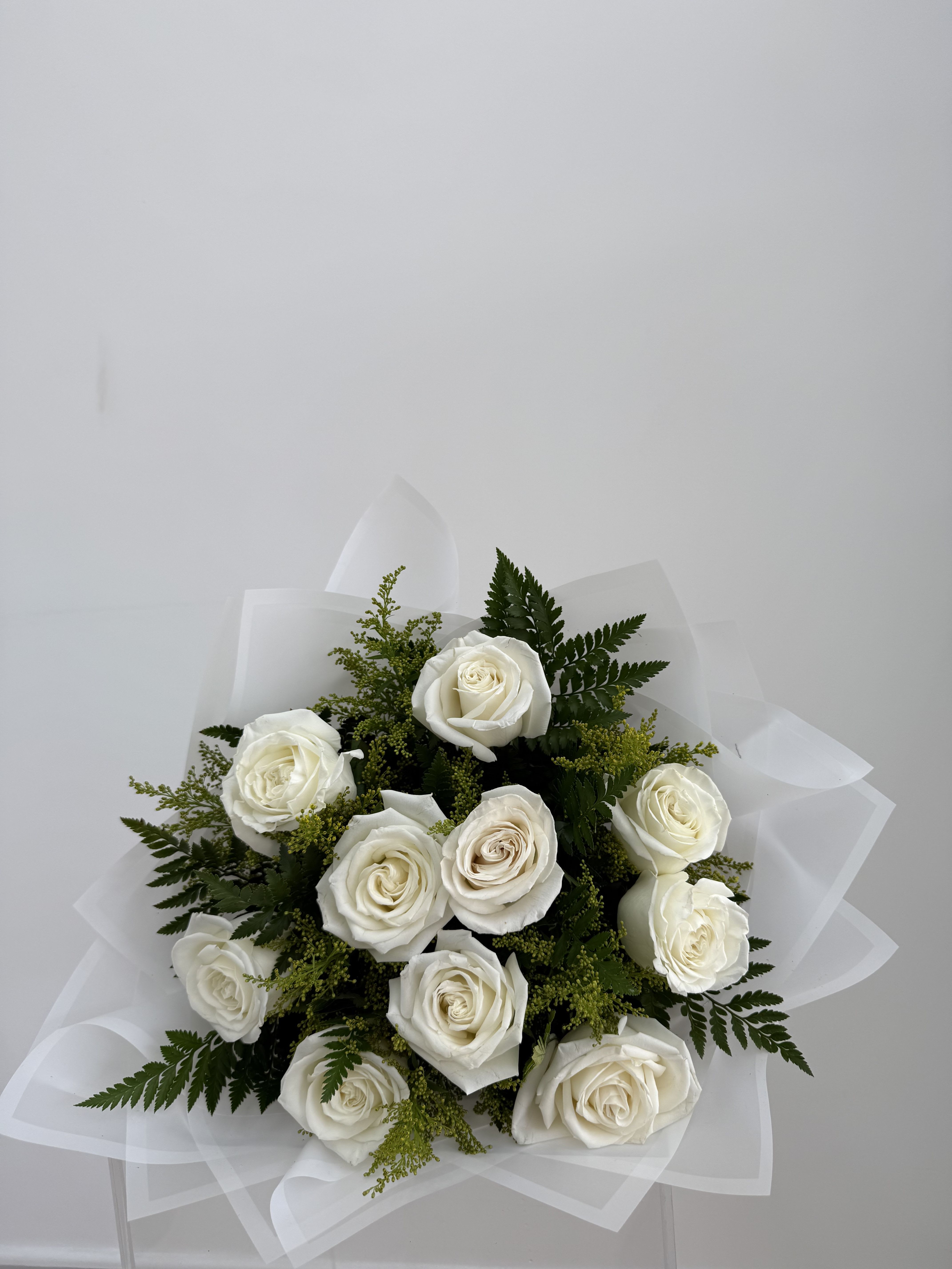 Bouquet of white roses with greenery and white wrap