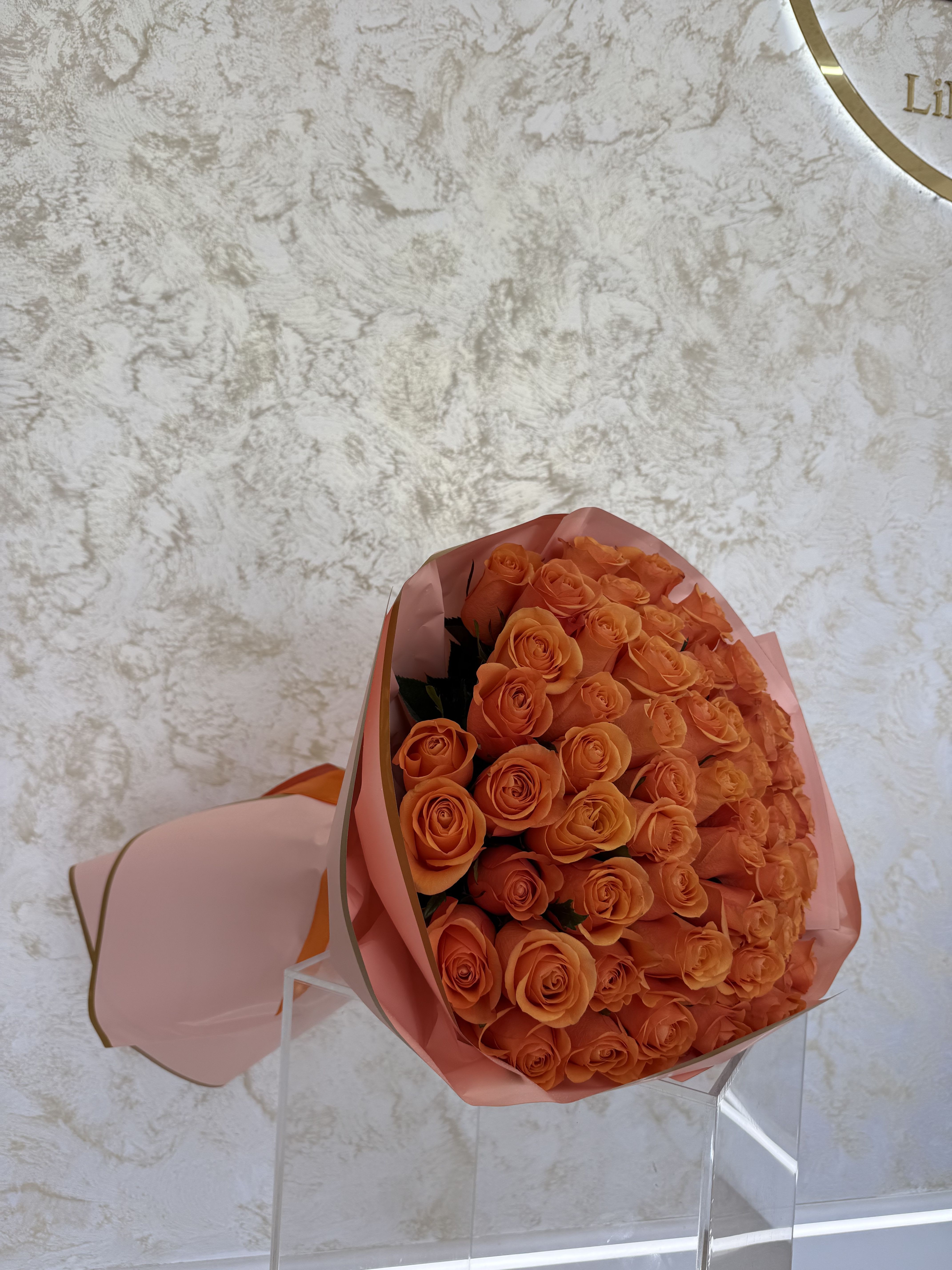 Bouquet of orange roses wrapped in pink paper
