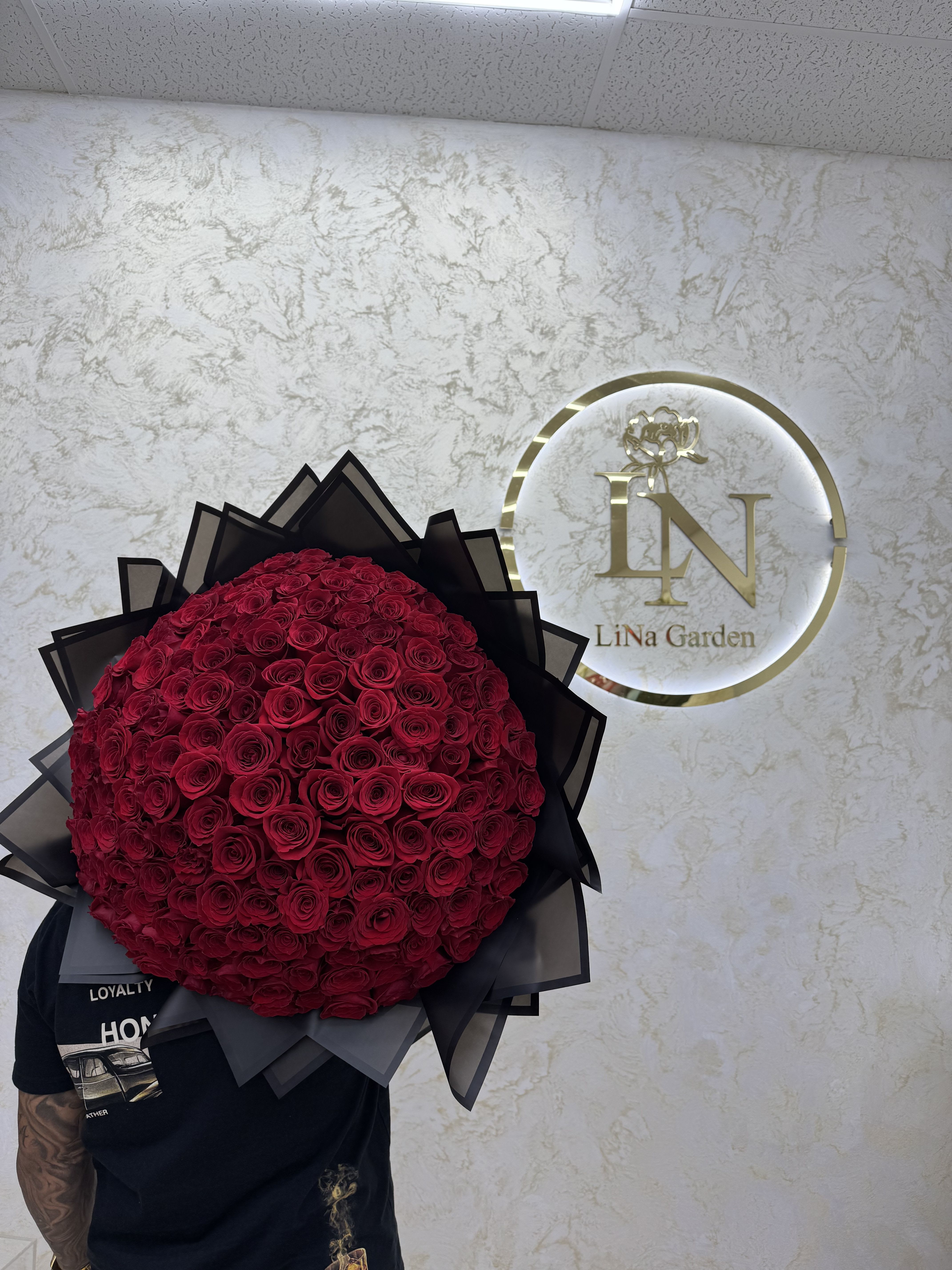 Large round bouquet of red roses wrapped in black paper