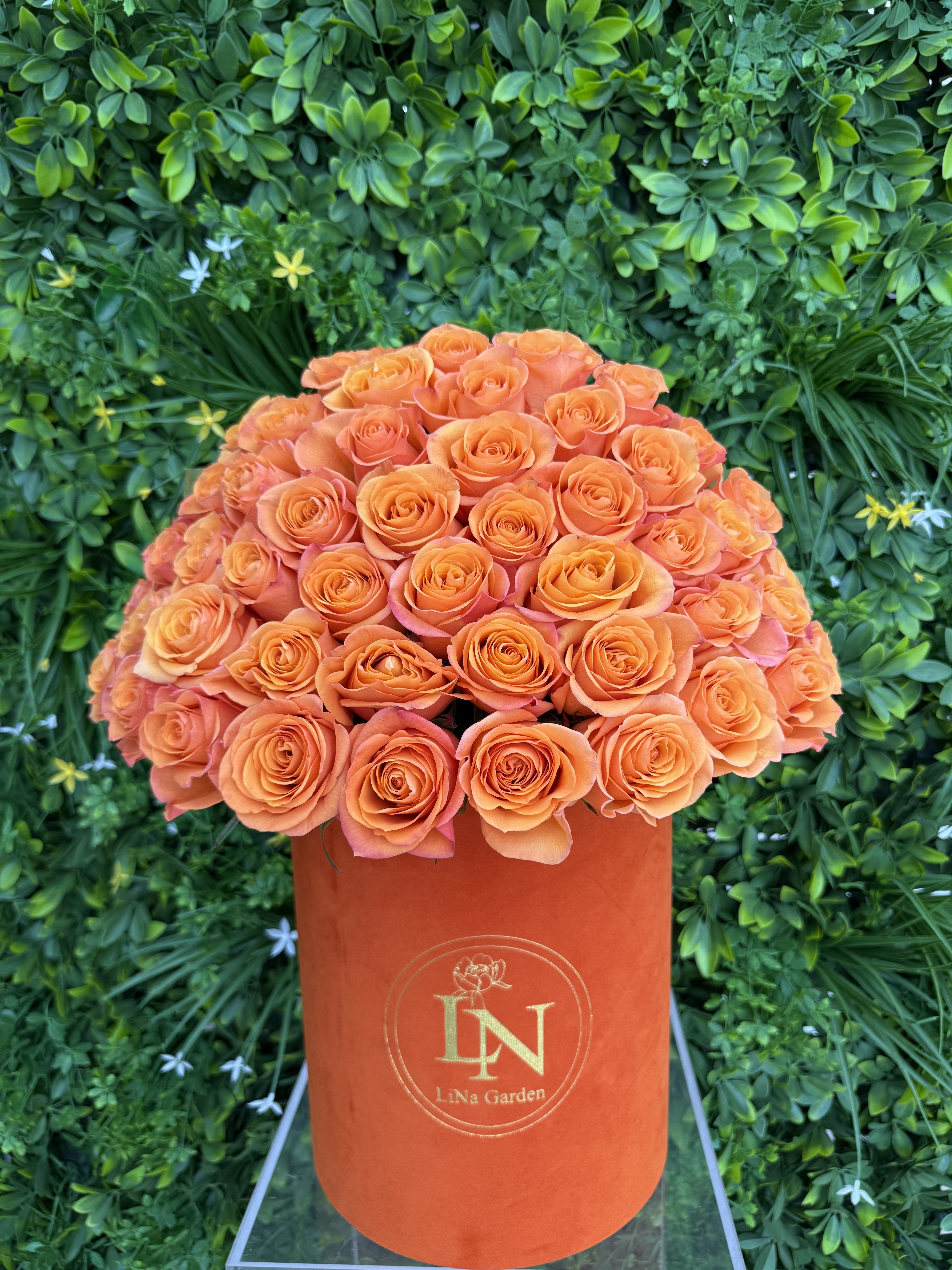Orange roses arranged in a tall orange hatbox