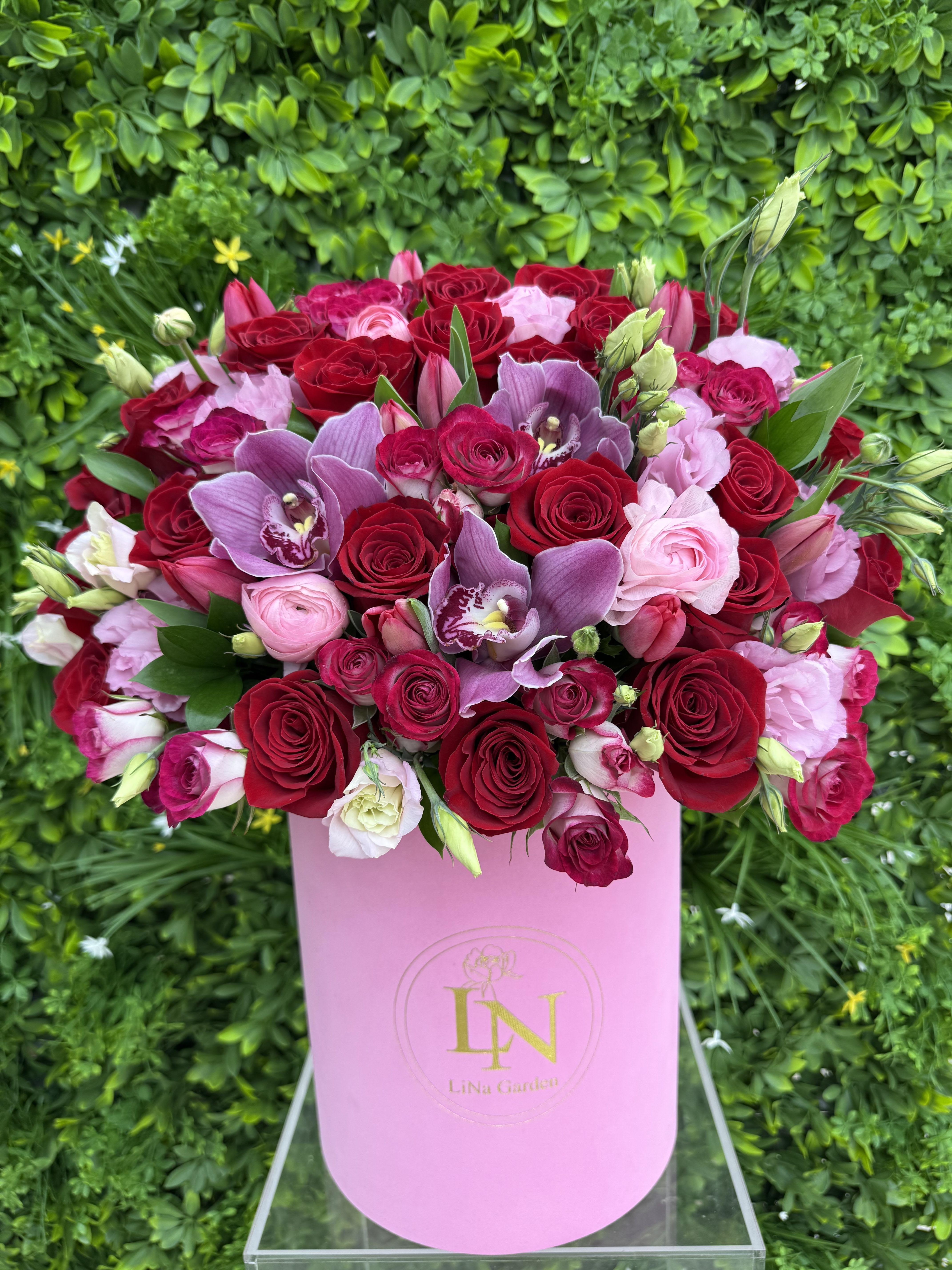 Pink hatbox arrangement with red and pink roses and purple orchids