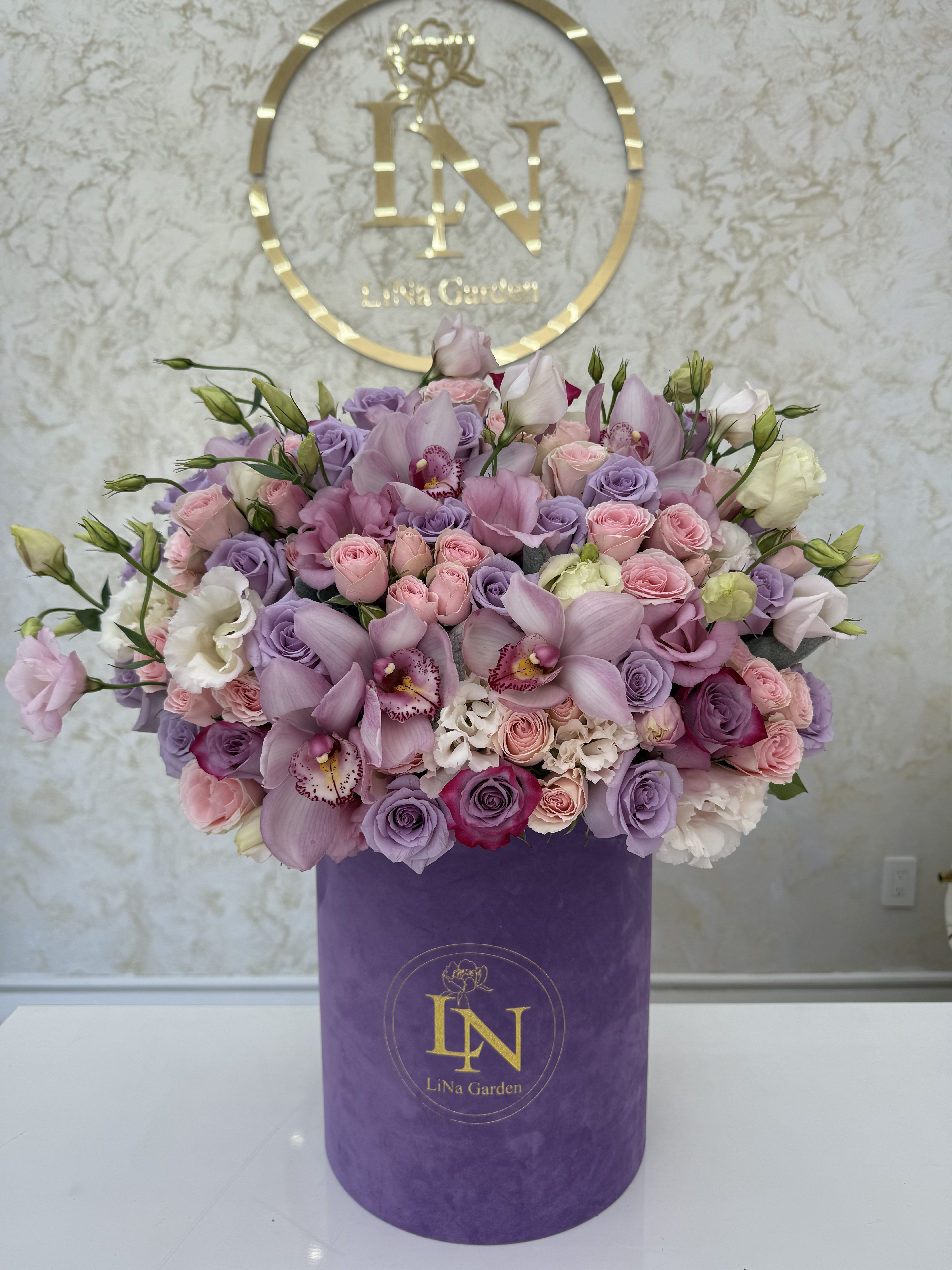 Large pastel bouquet of pink and lavender flowers in a purple box