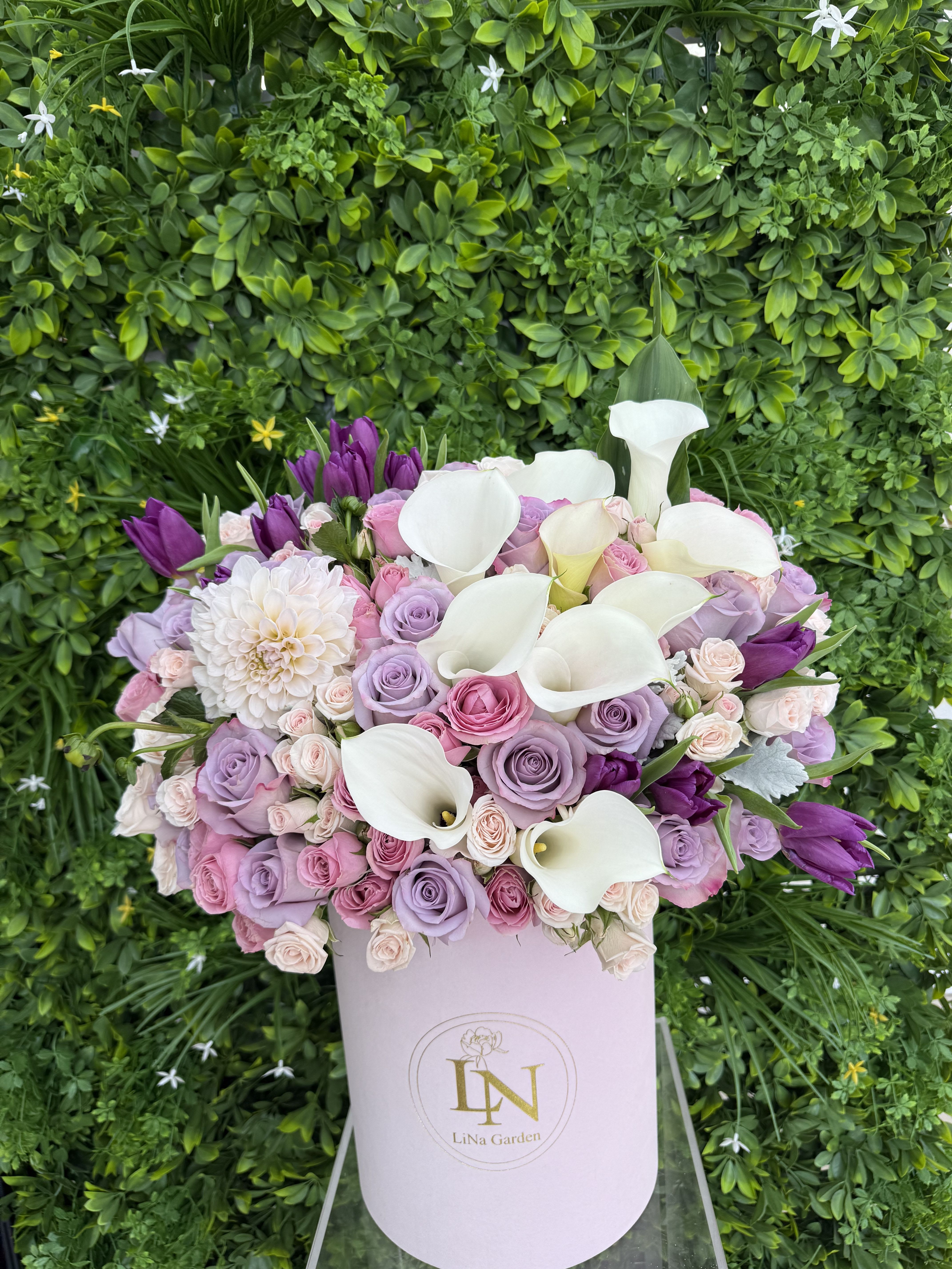 Lavender and pink roses with white calla lilies in a pale pink box