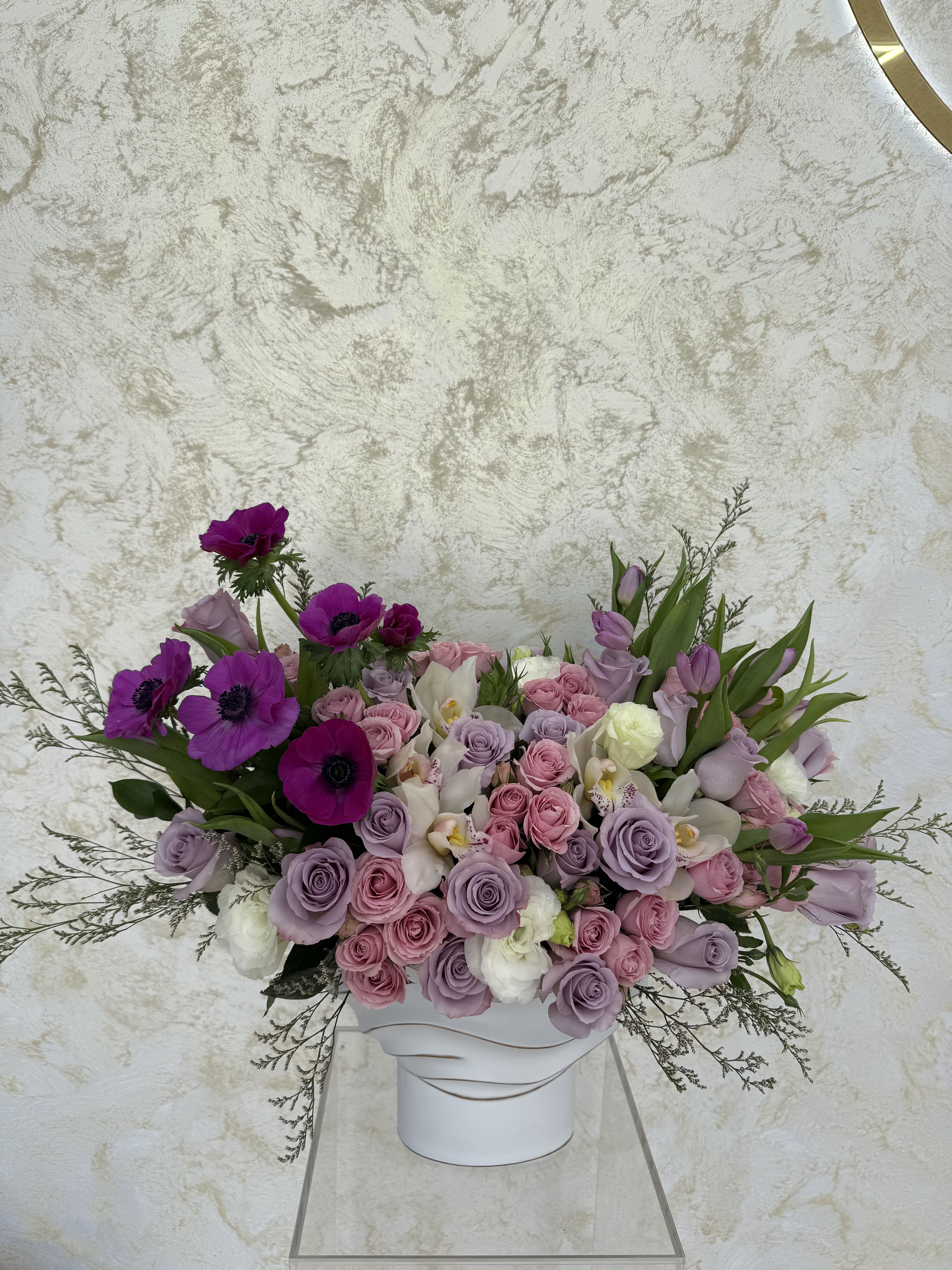 Lavender and pink roses with purple anemones in a white vase