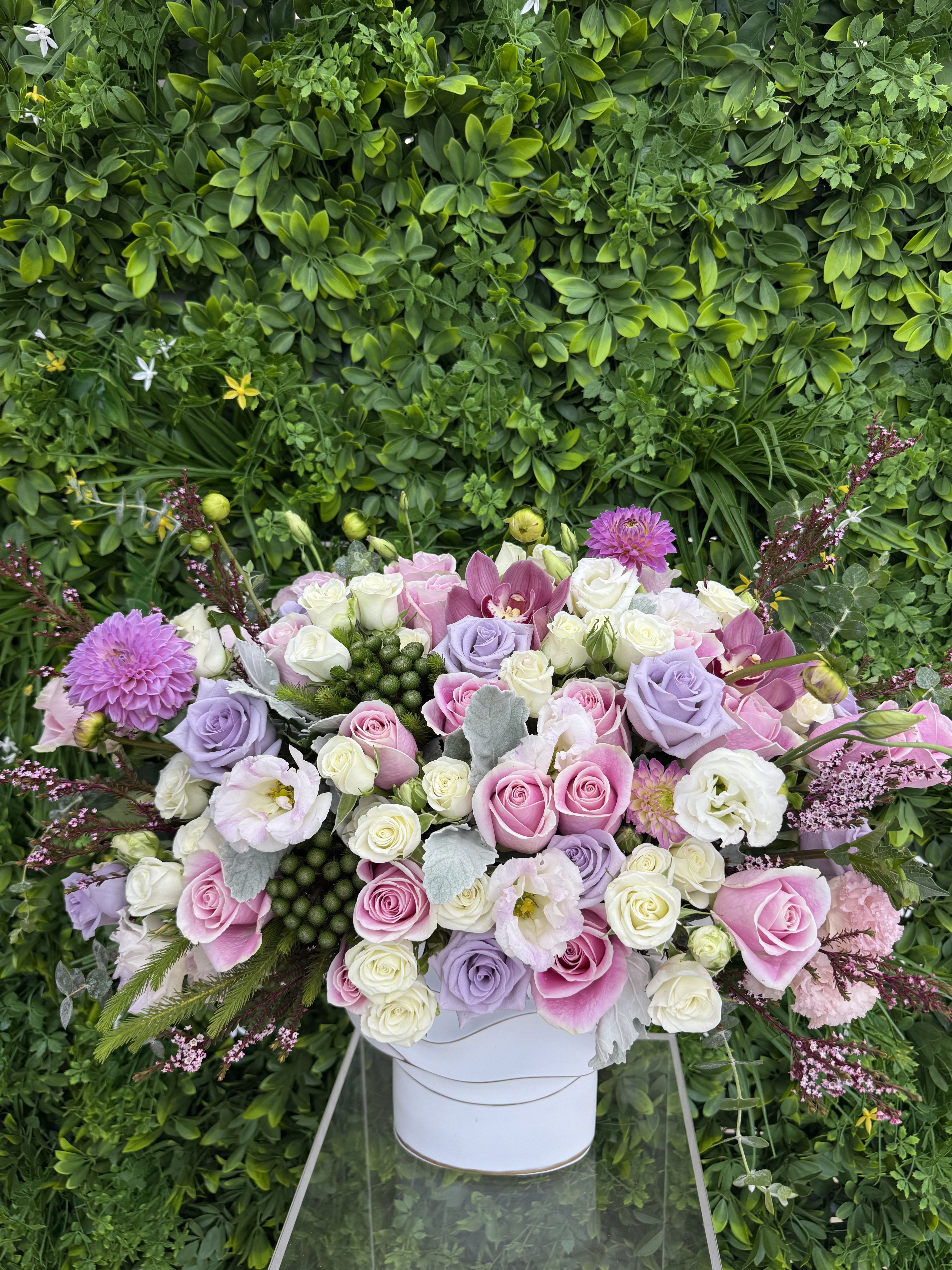 Large pastel bouquet of roses, orchids, and lisianthus in a white container