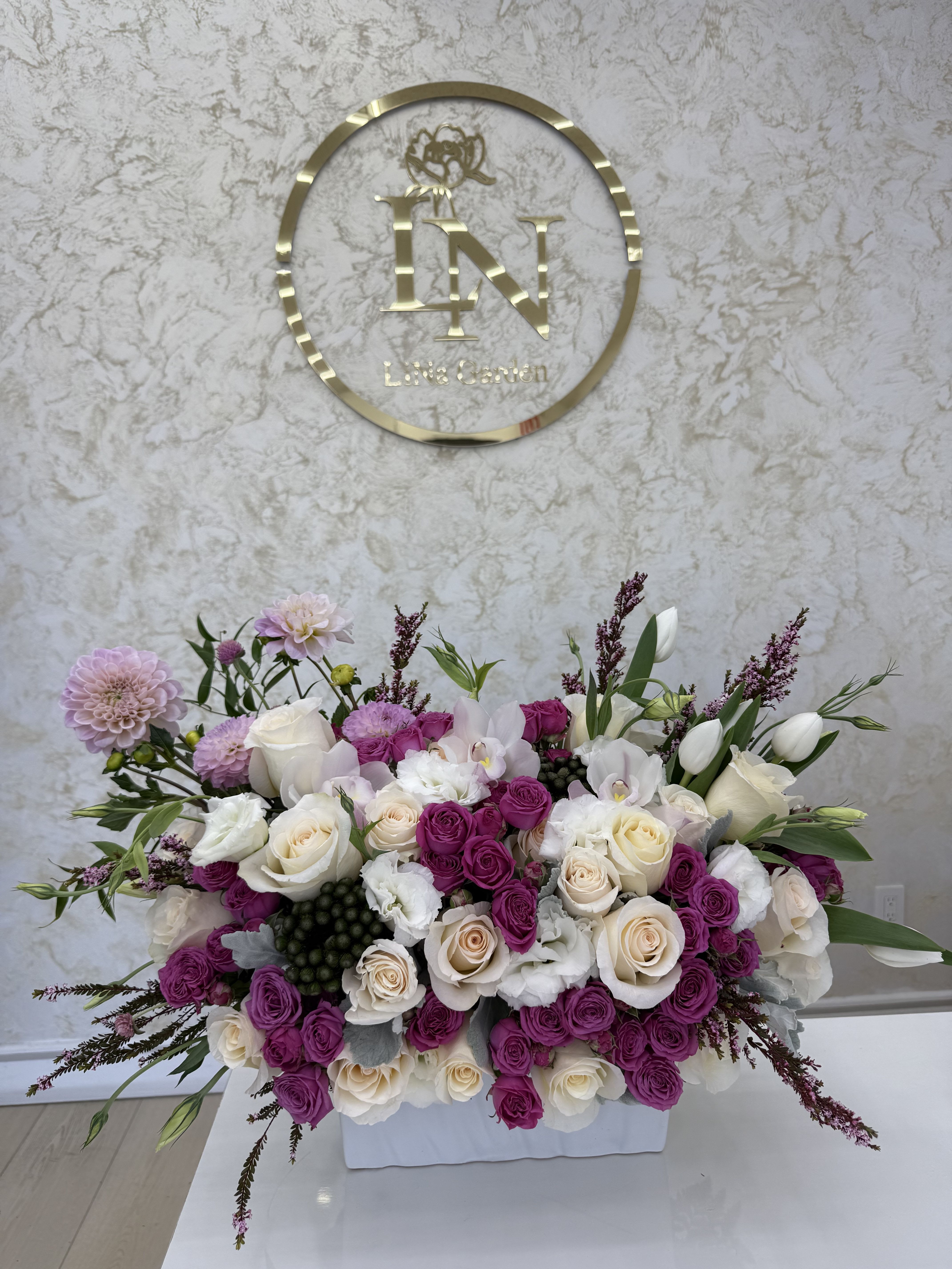 Large pink and white floral arrangement in a white container