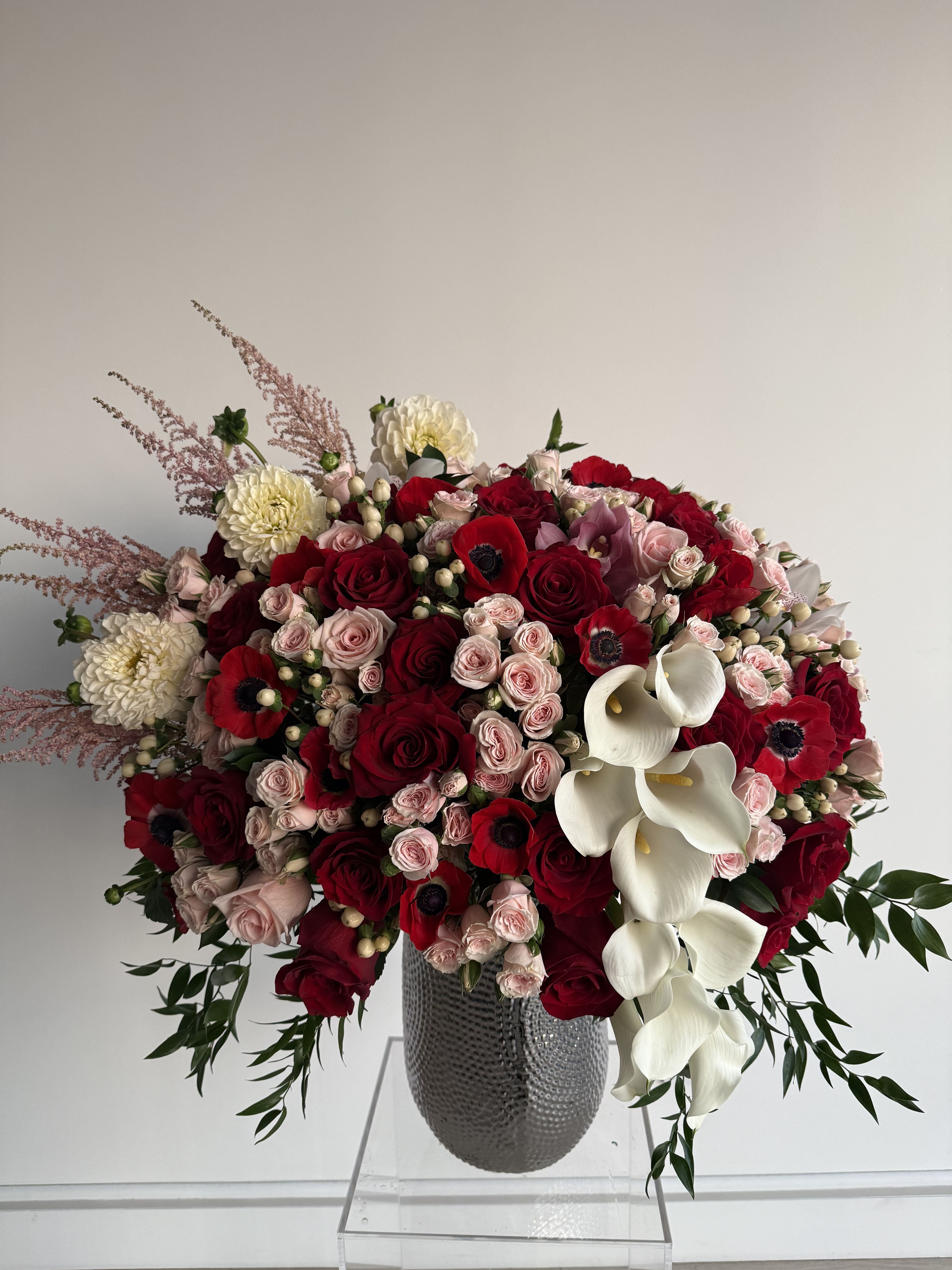Large bouquet of red and blush roses with white calla lilies in a gray vase