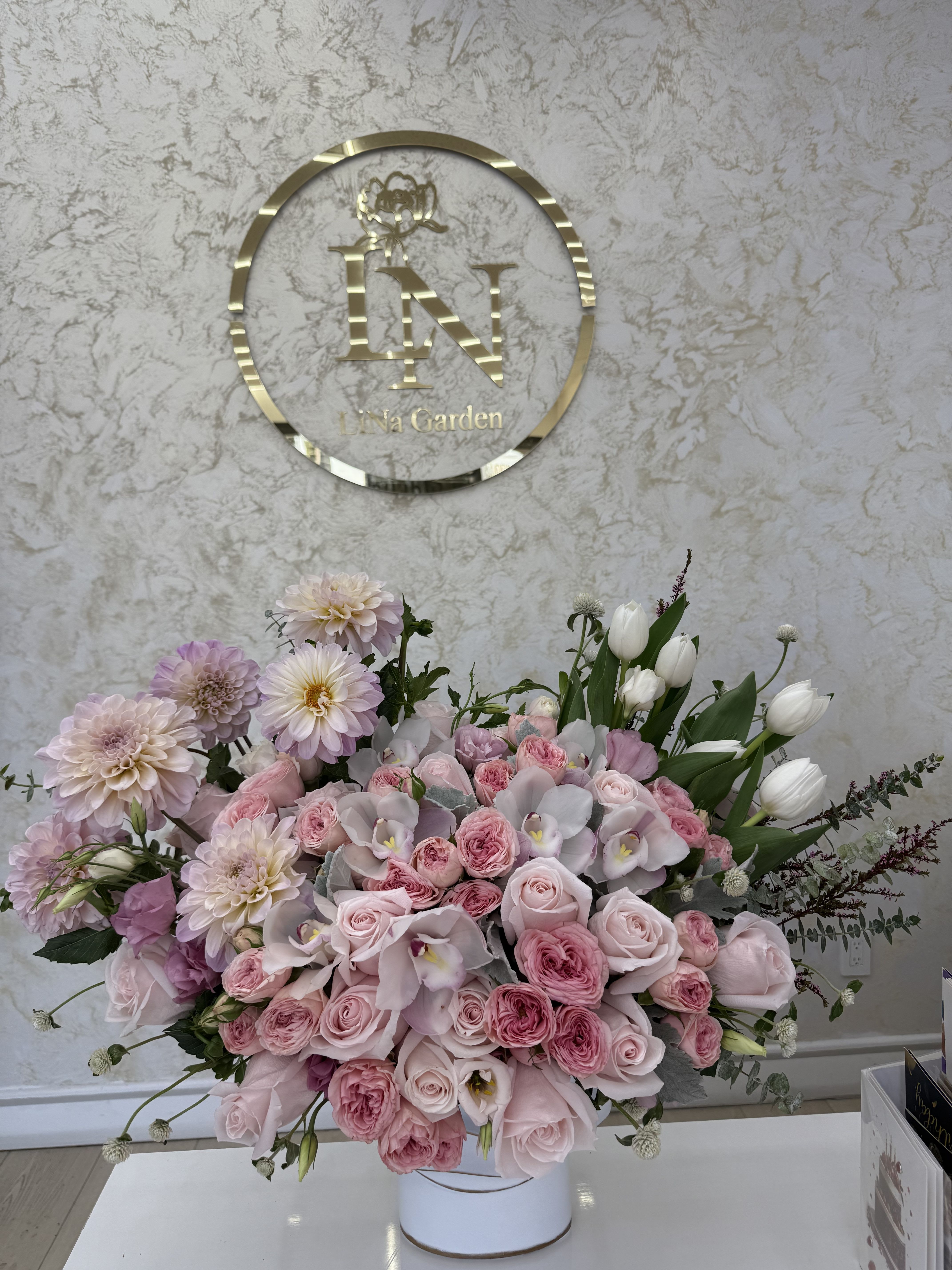 Large pink floral arrangement in a white vase with roses and tulips