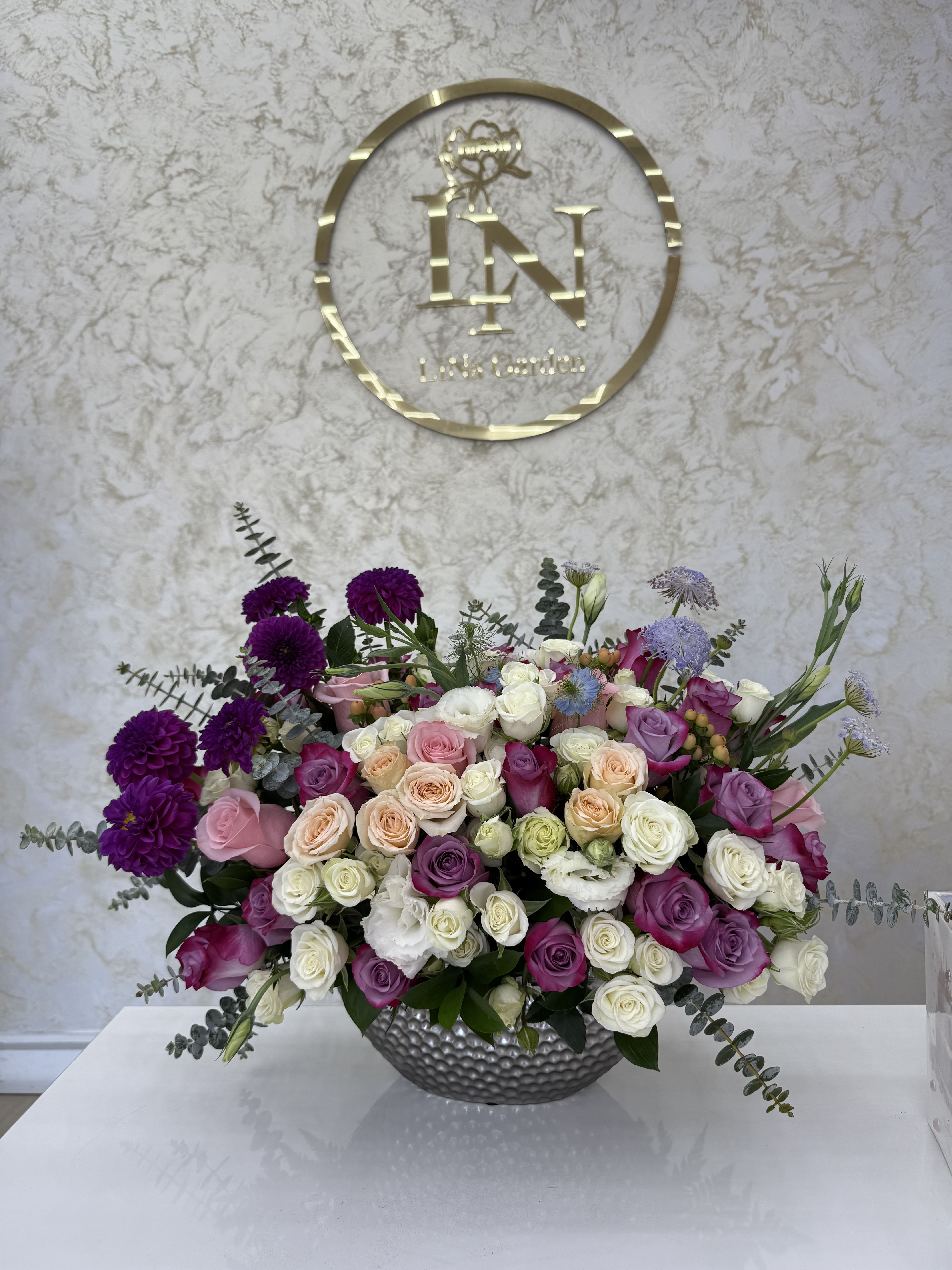 Large mixed bouquet of roses and purple blooms in a silver vase