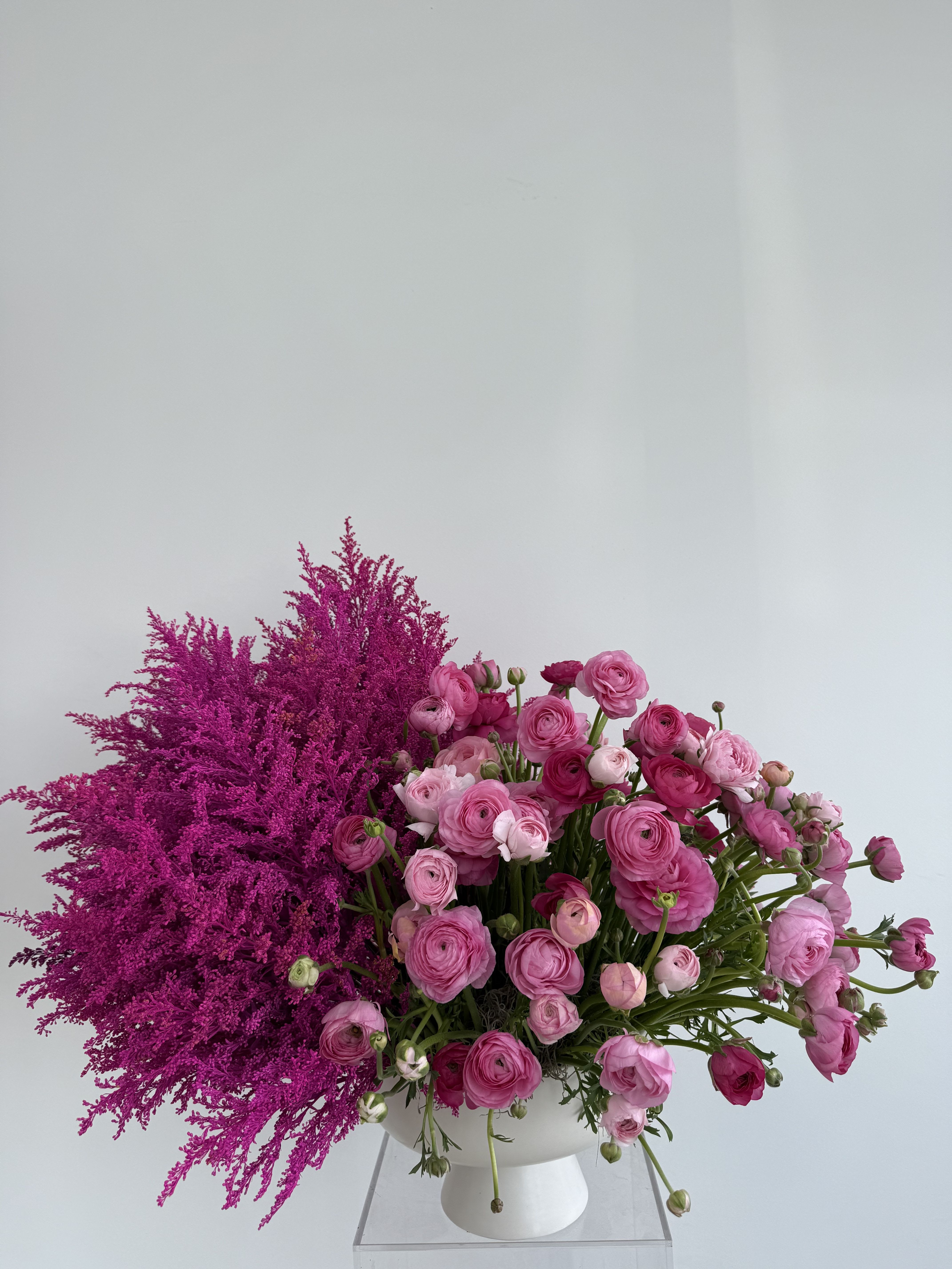 Pink ranunculus arrangement in a white vase with magenta filler