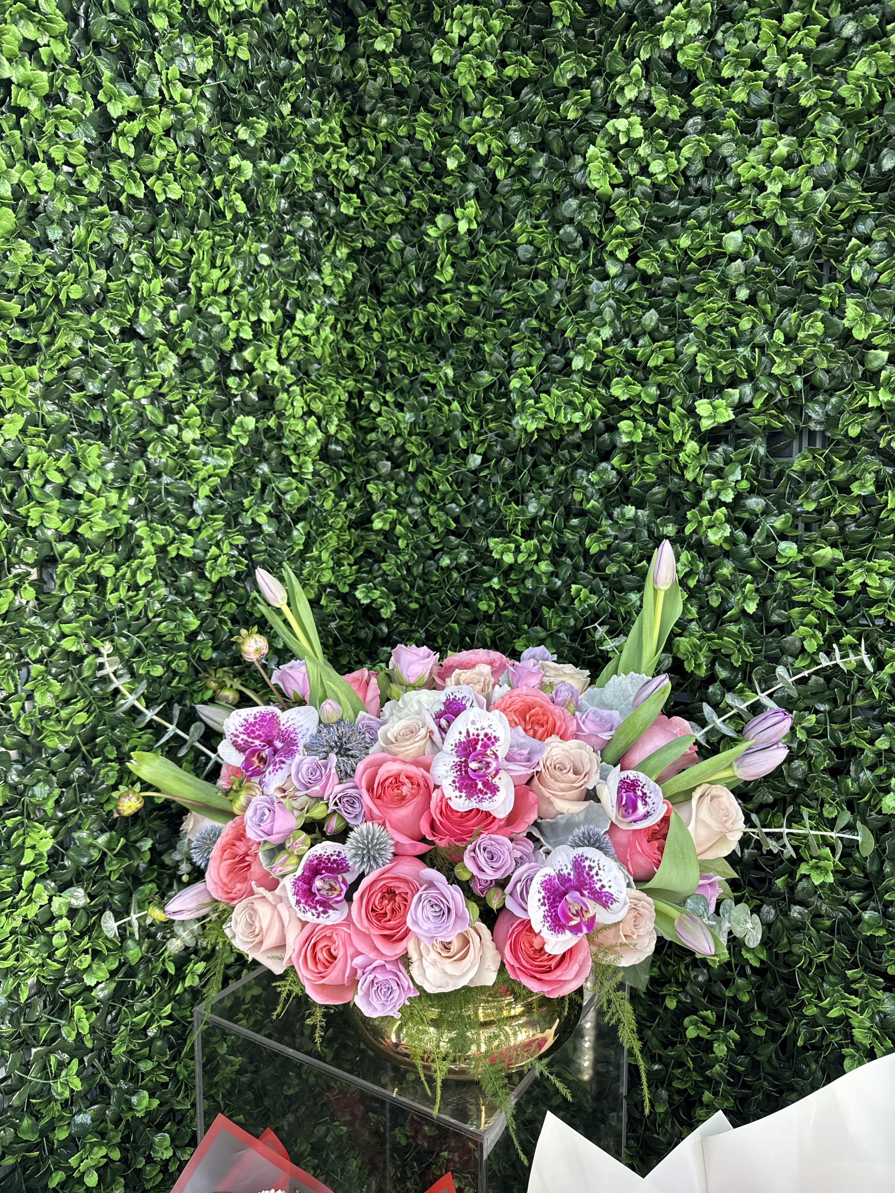 Pink and lavender rose bouquet with orchids in a gold vase