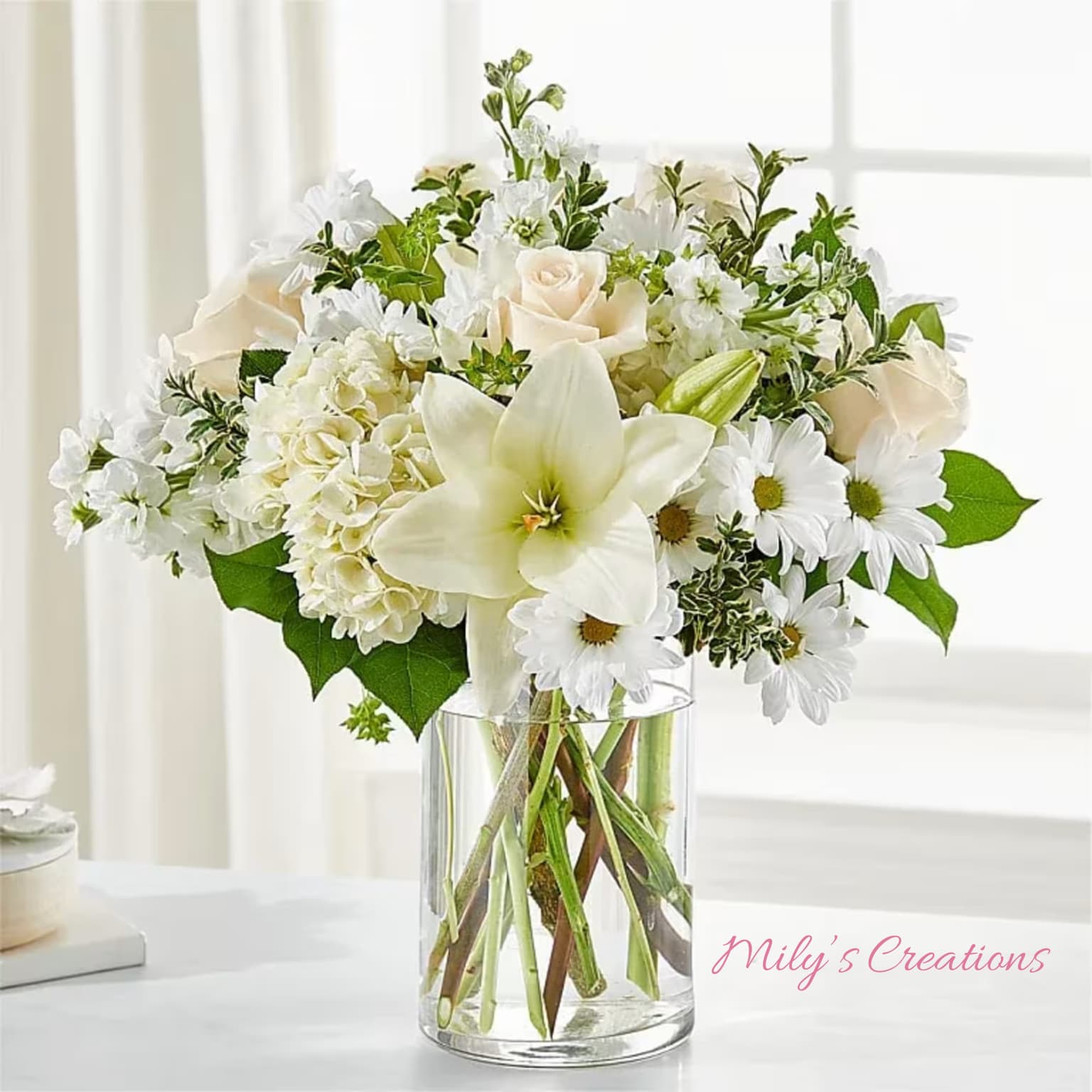 White lilies, roses, hydrangeas, and daisies in a clear glass cylinder vase
