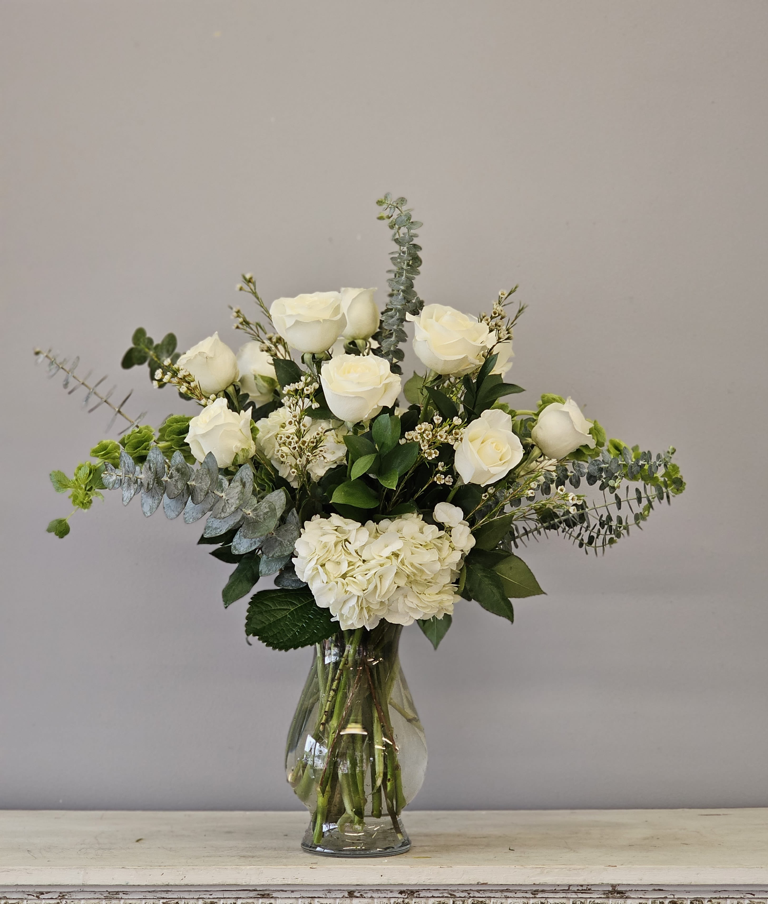 Classic Elegance - One dozen premium white roses arranged in a vase with hydrangea included.