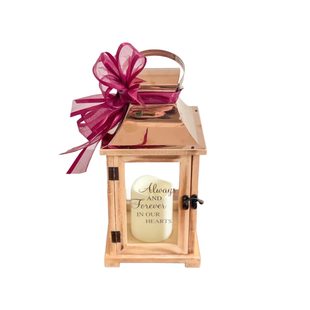 Wood and copper memorial lantern with a candle and burgundy ribbon bow on the handle.