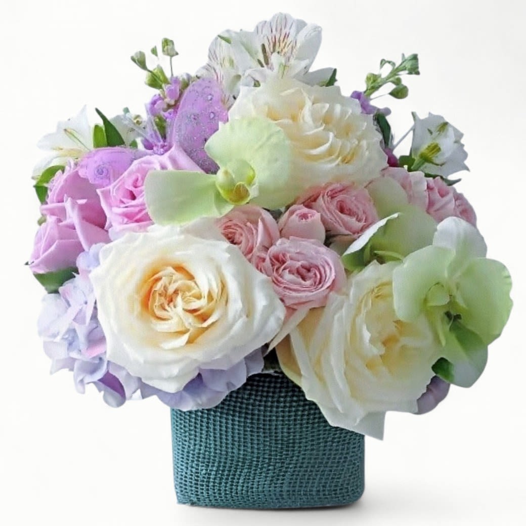Pastel arrangement of roses, orchids, and mixed blooms in a teal textured cube vase