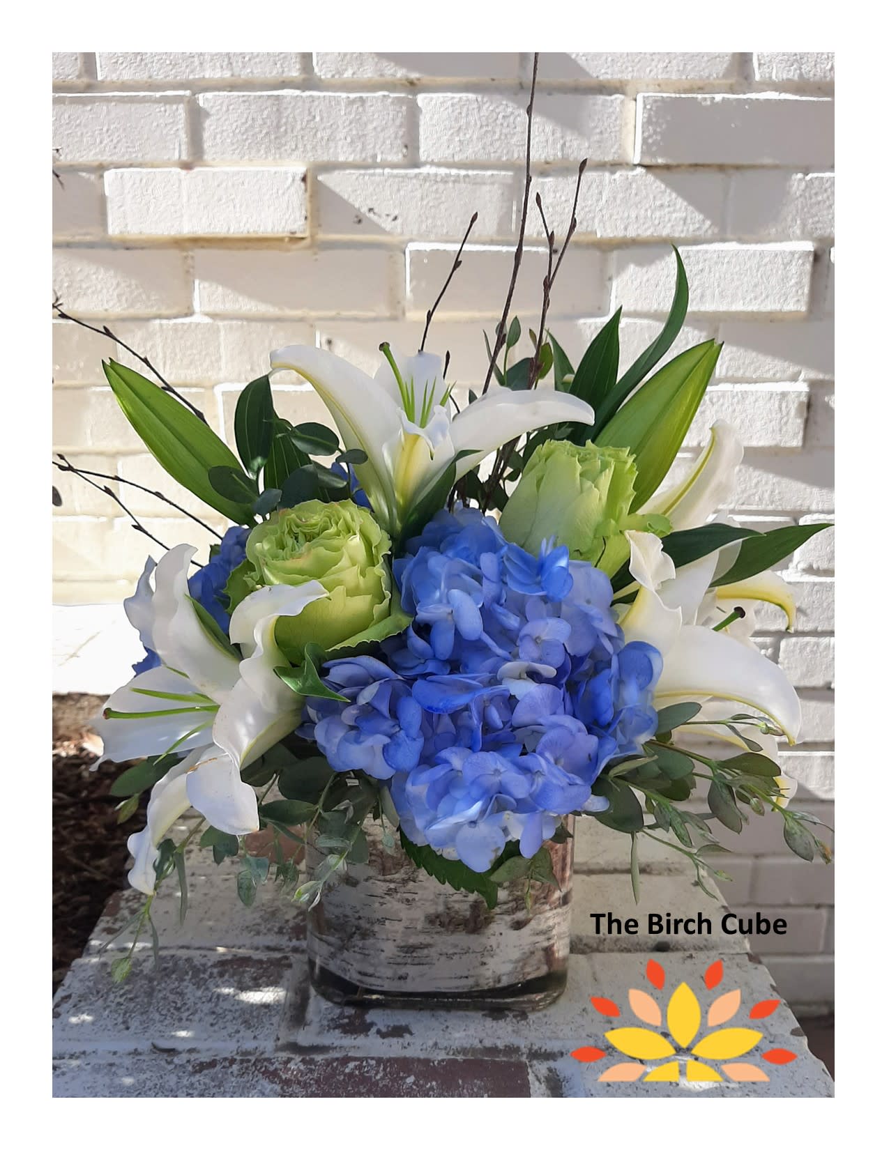 The Birch Cube - Classic blue, white and green tones make up this eye catching bouquet. Roses, lilies and hydrangea make up this premium birch lined cube. Perfect for sympathy, corporate gifts, or just for someone who hates all things pink! Approx: 7"W X 10"H