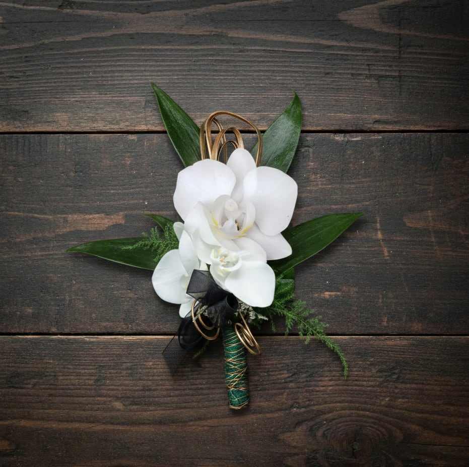White orchid boutonniere with black ribbon and gold wire accents on a dark wood surface