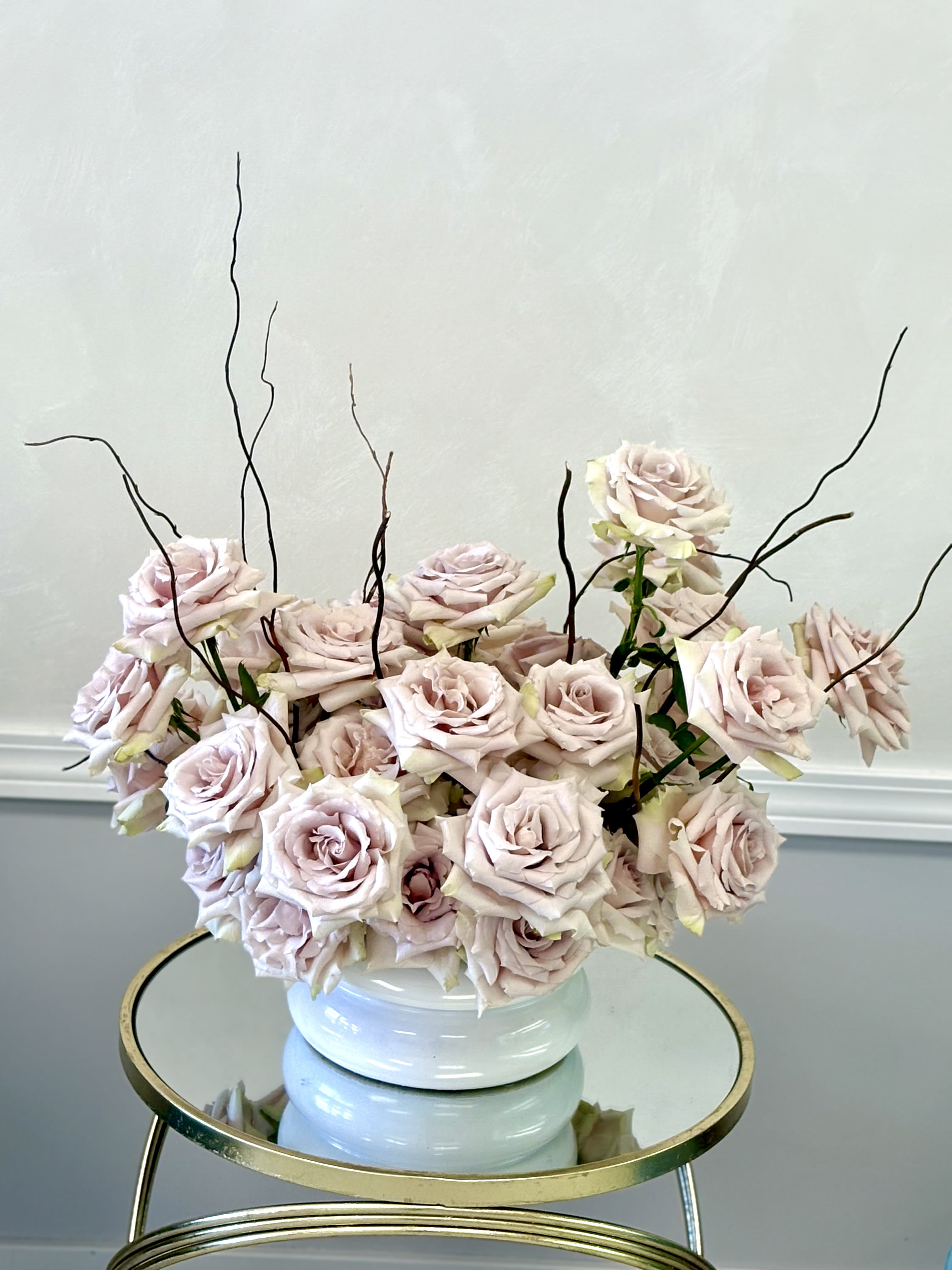 Blush Whisper Roses By VLM Flowers - A soft and elegant arrangement of blush roses styled in a modern low vase, accented with natural branches for a contemporary touch. Romantic and refined, it’s perfect for adding subtle beauty to any space.