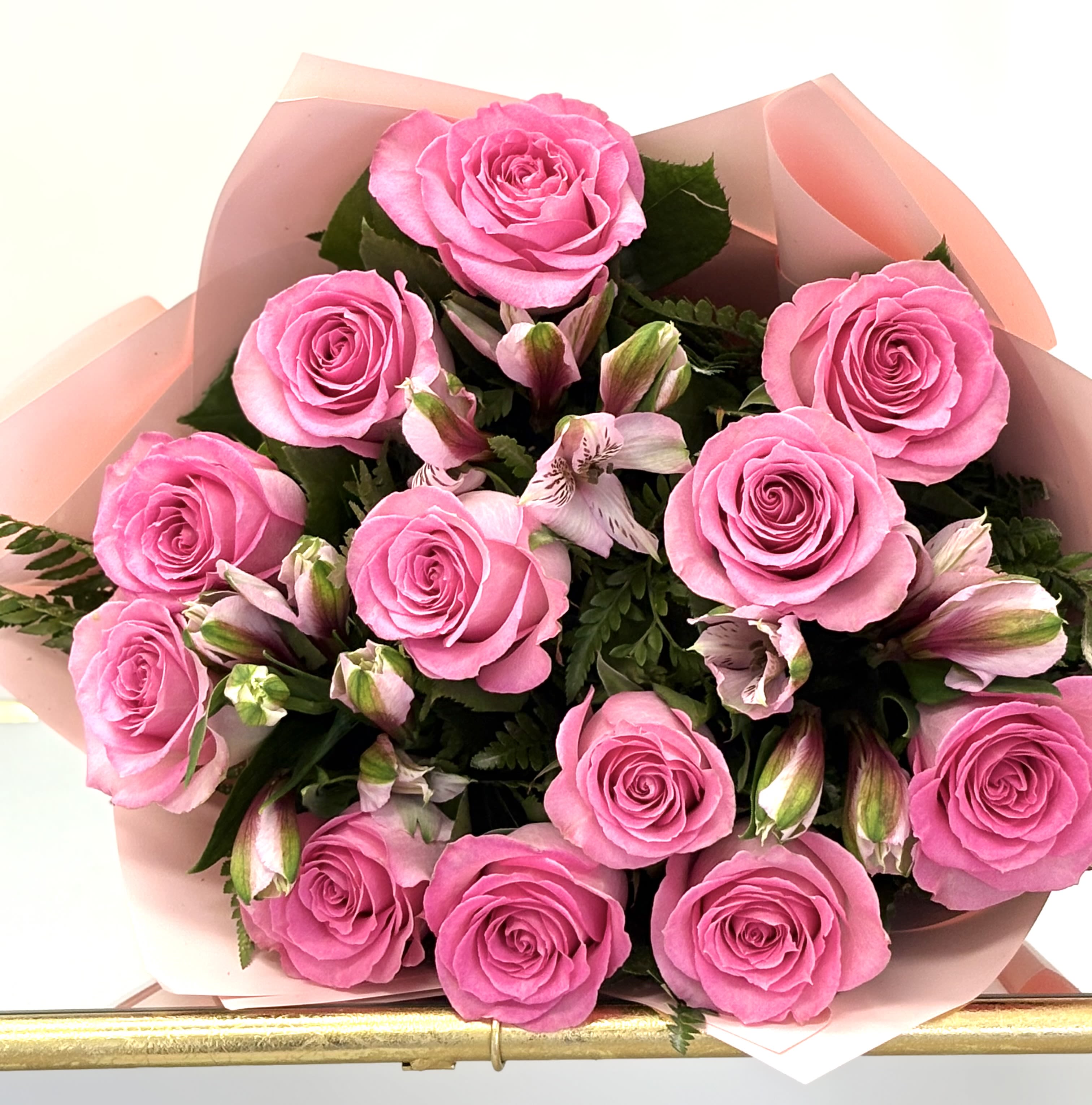 Bouquet of pink roses and light pink alstroemeria wrapped in soft pink paper