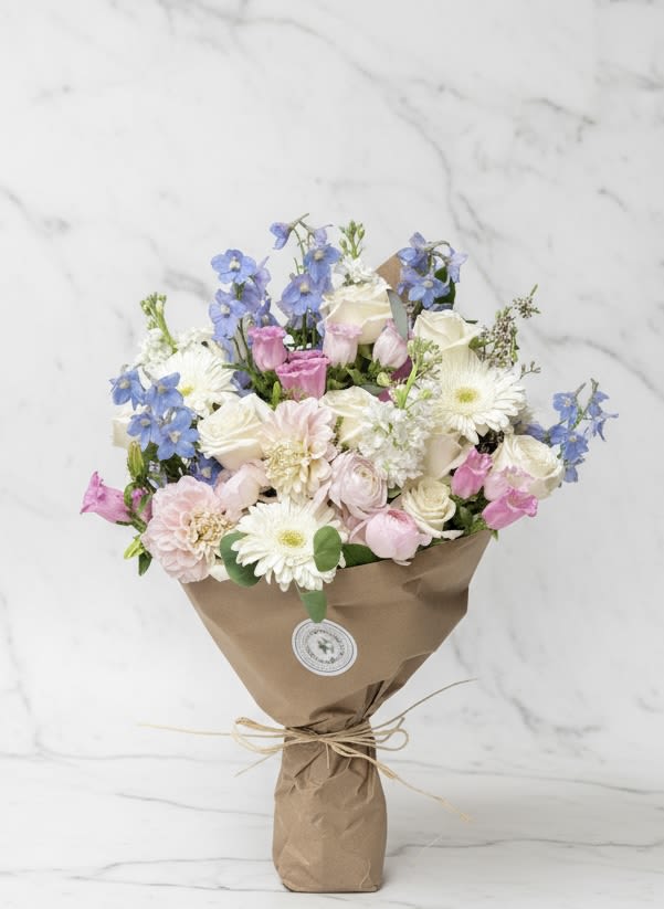 Blush and Blue Wrapped Bouquet - Delicate and timeless, our Blush and Blue Wrapped Bouquet features soft pink roses, airy blue blooms, and creamy white accents, artfully arranged in natural kraft paper. Perfect for birthdays, anniversaries, or heartfelt gestures, this pastel bouquet embodies elegance and charm. Handcrafted with fresh seasonal flowers and wrapped for a modern, romantic touch — a beautiful statement of grace and serenity. (Pictured in premium)  Keywords: blush and blue bouquet, pastel flower arrangement, wrapped bouquet delivery, elegant floral gift, San Francisco florist 