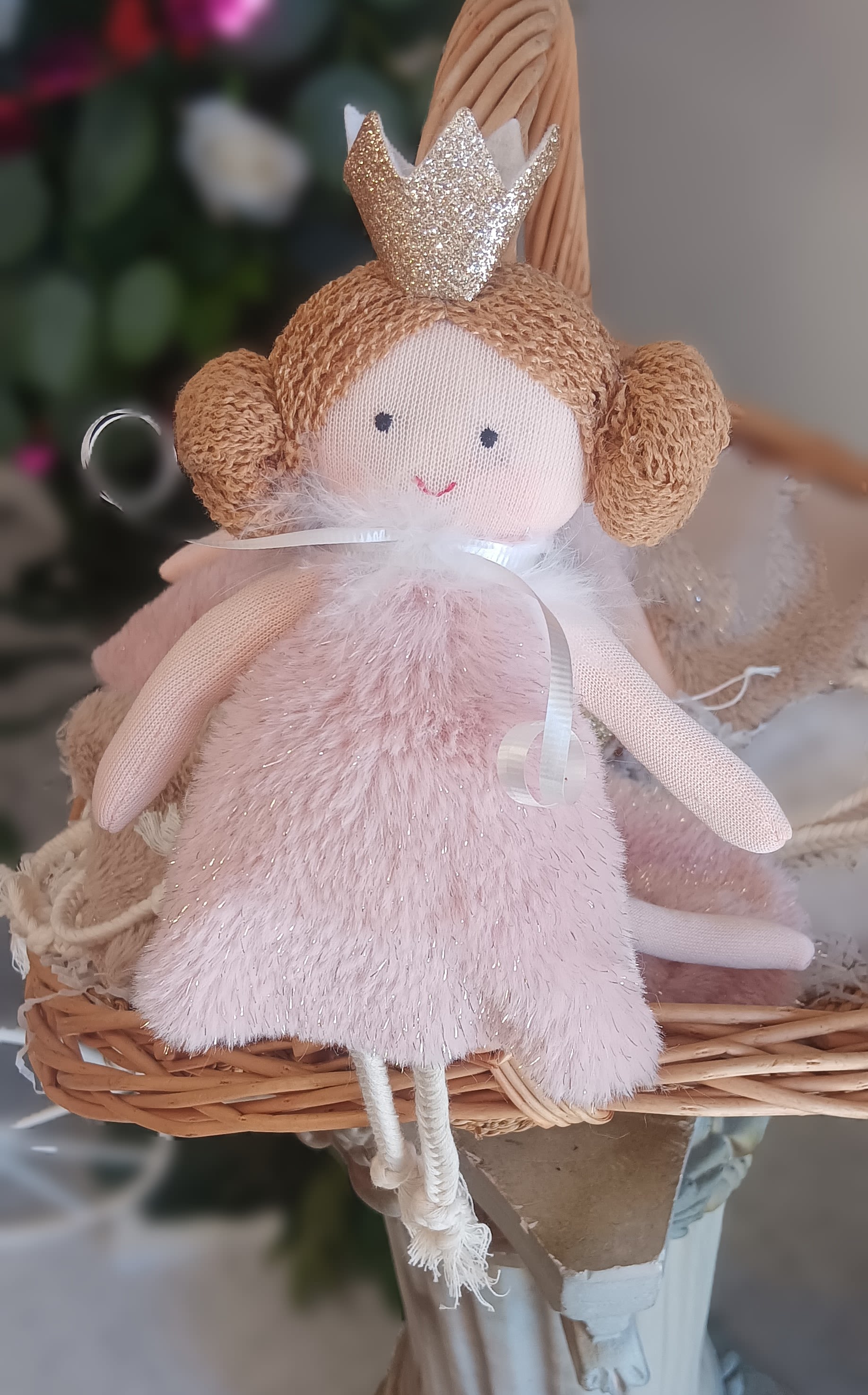Plush angel doll with a glitter crown in a wicker basket