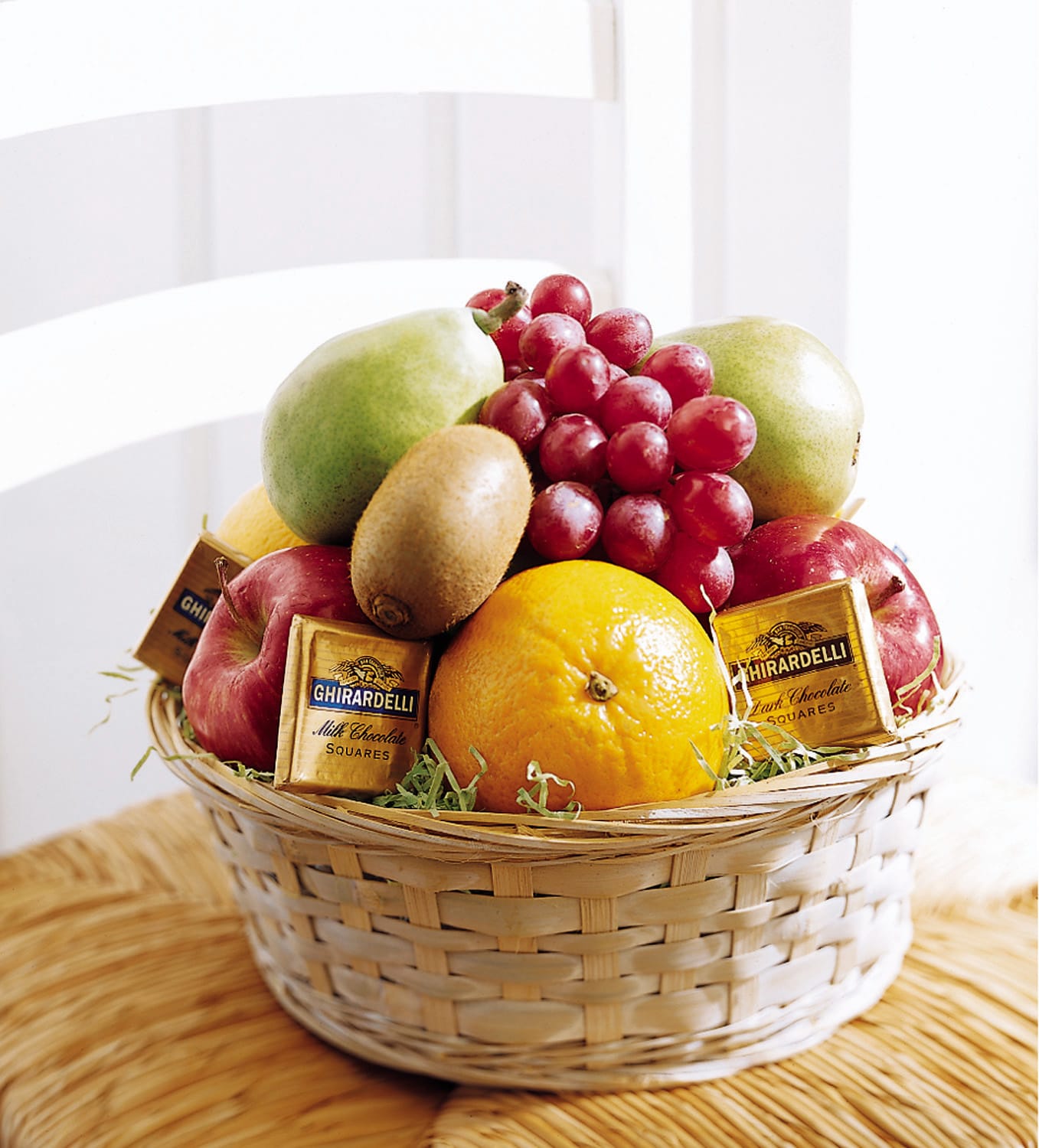 Gift basket filled with assorted fresh fruit and wrapped chocolate squares in a woven light-colored basket