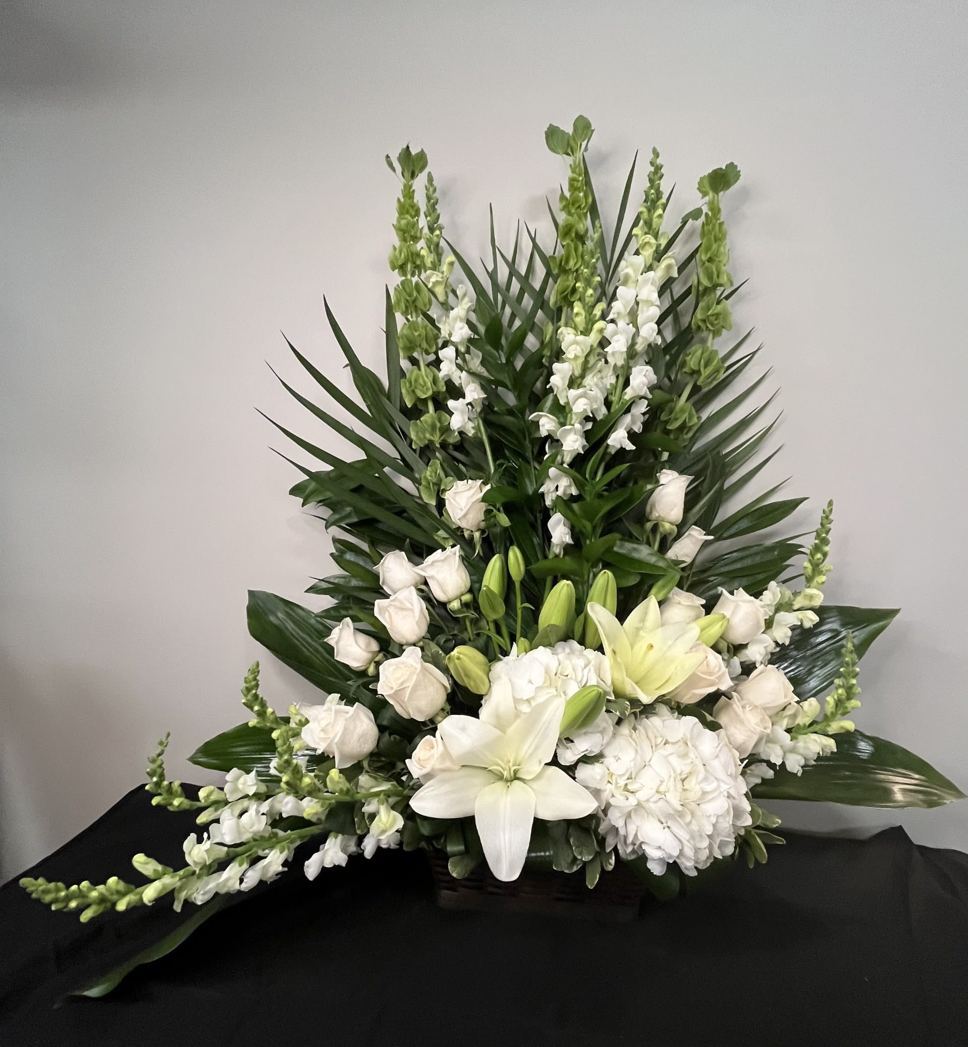 Garden of Peace by Chasing Petals - Garden of Peace is a serene, elegant arrangement designed to evoke calm and quiet reflection. Featuring soft white blooms - graceful lilies, delicate roses, lush hydrangea and tall snapdragons - this design in complimented by rich greenery that adds depth and balance. Its gentle palette and structured shape create a sense of harmony, making it a beautiful tribute for moments of remembrance, sympathy or peaceful celebration.