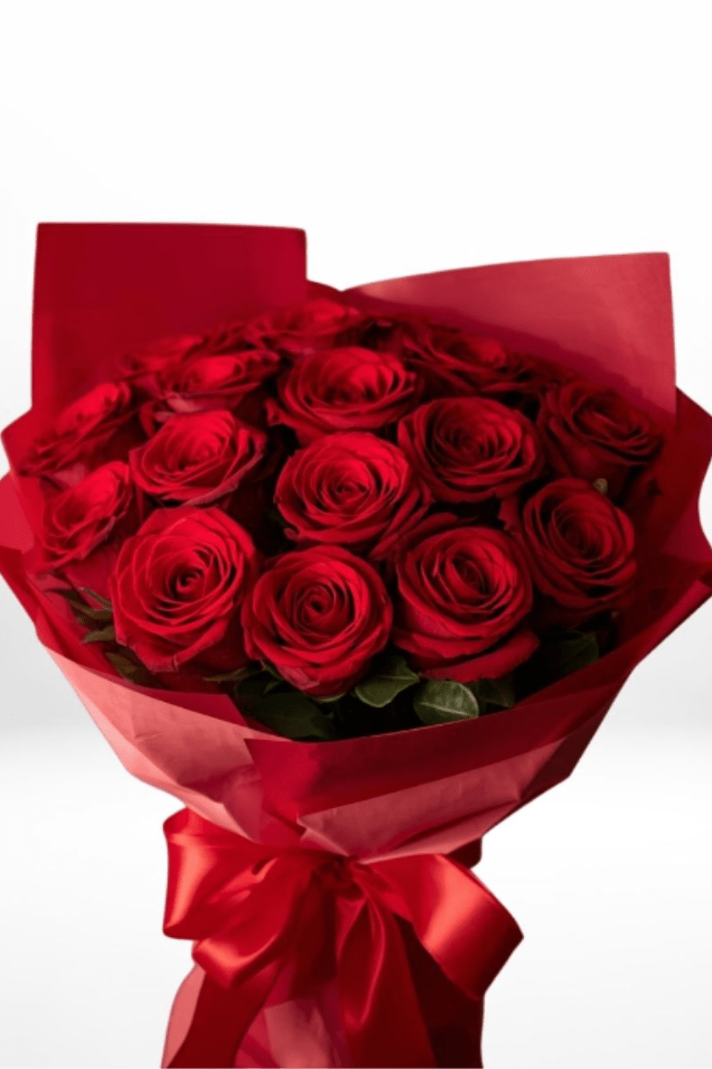 Hand-tied bouquet of red roses wrapped in red paper with a satin bow