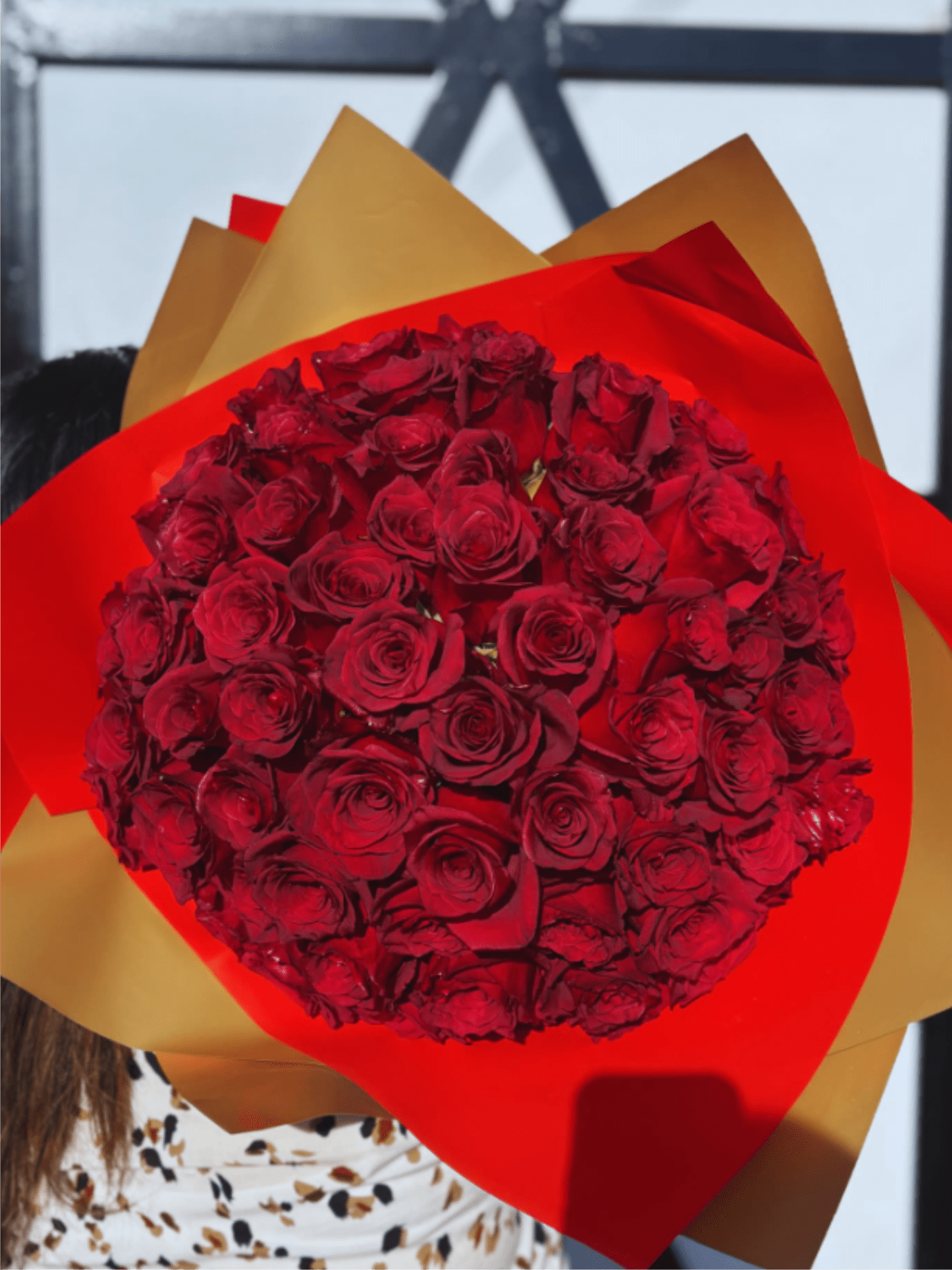 Large bouquet of red roses wrapped in layered red and gold paper
