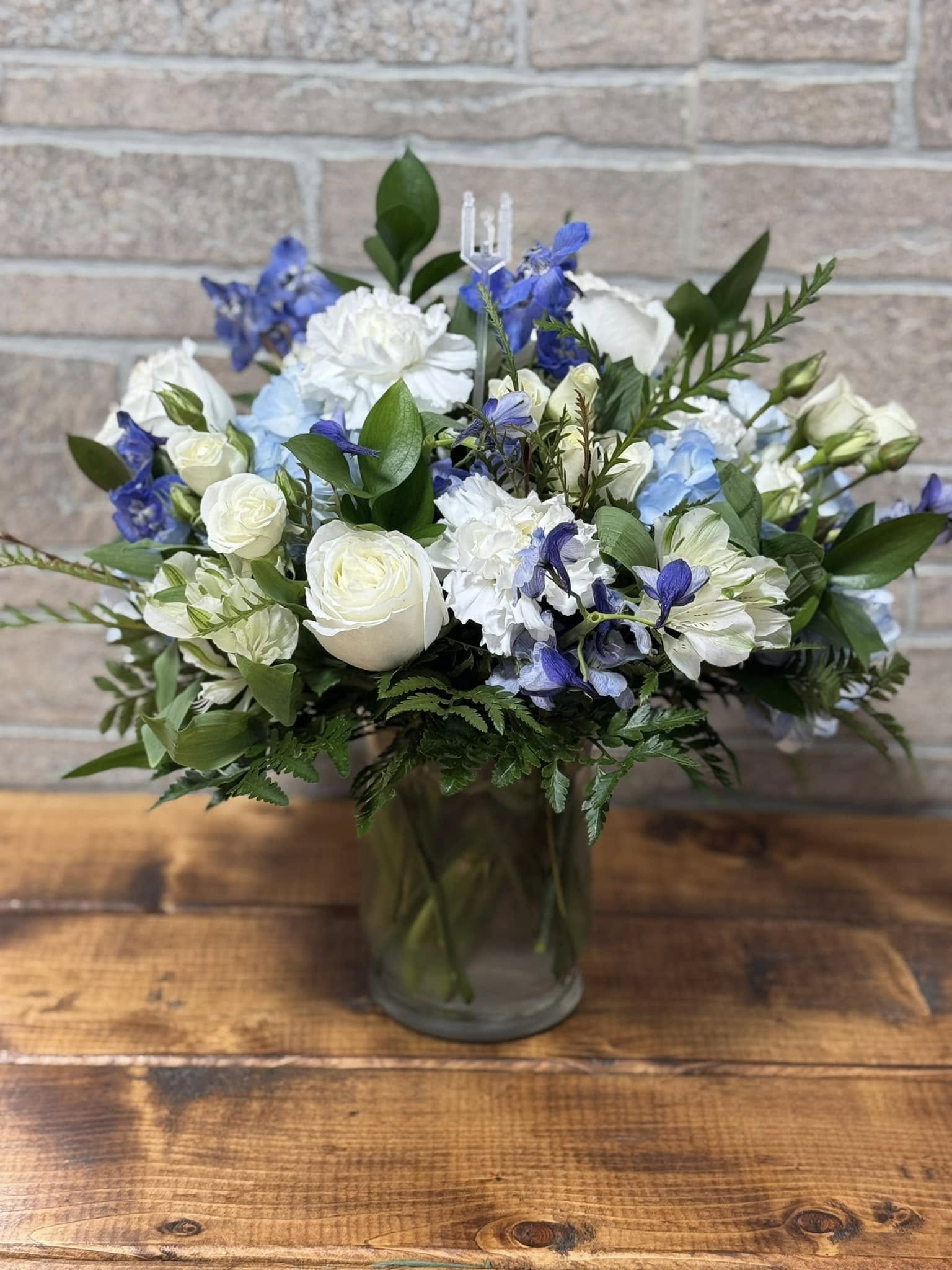 White and blue mixed flower arrangement in a clear glass vase.