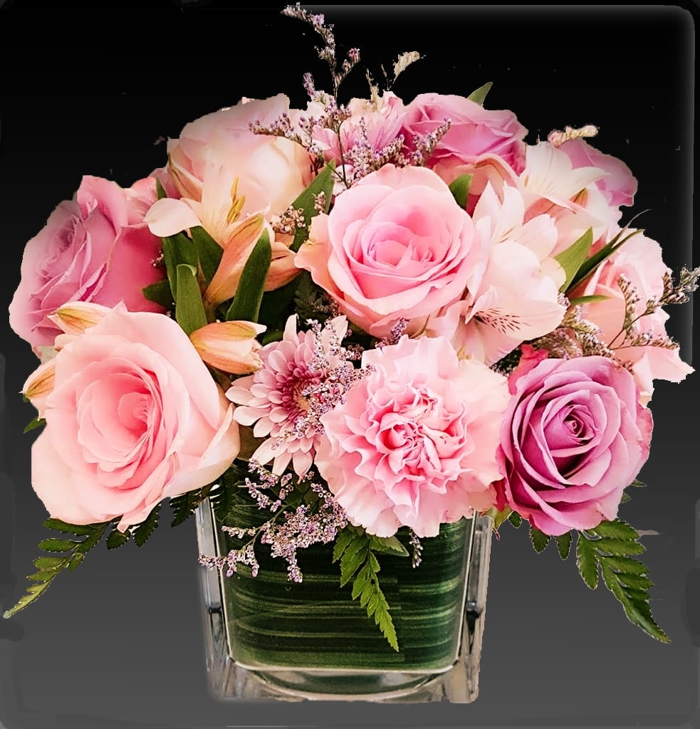 Pink and lavender roses with carnations and mums in a square glass vase.