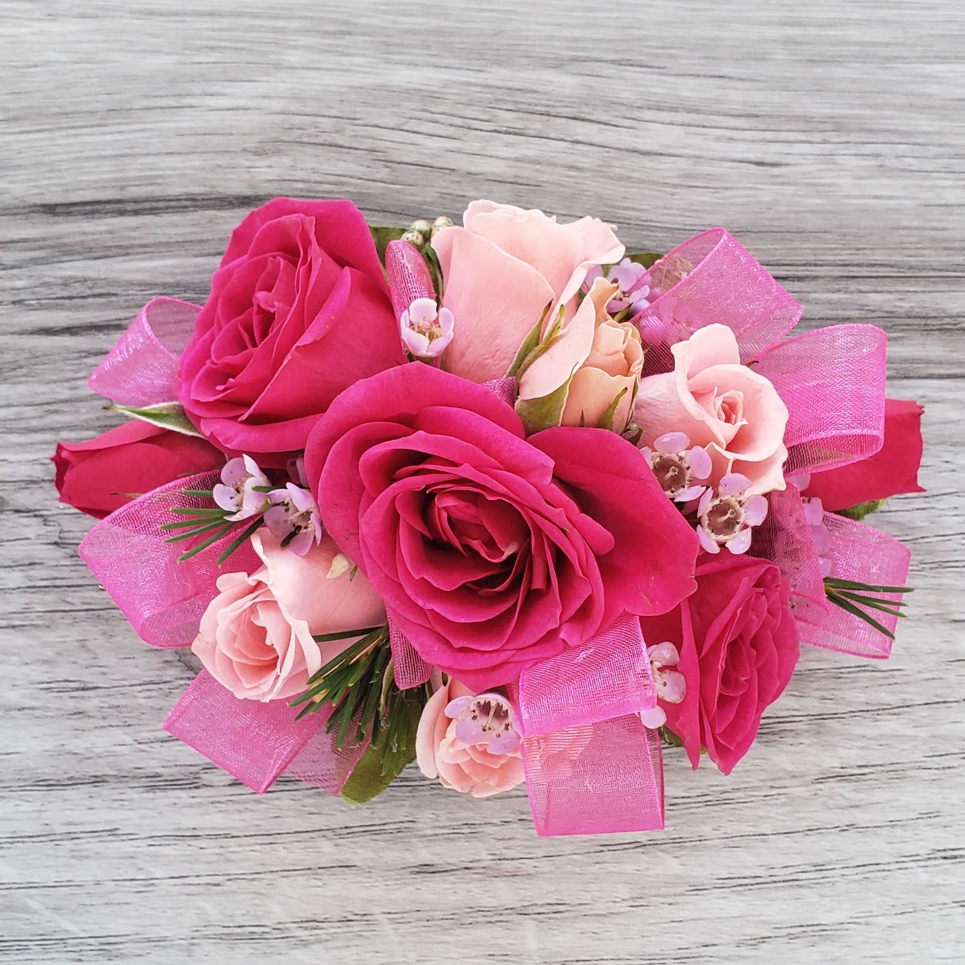 Hot Pink Corsage - This corsage features a mix of hot pink and light pink roses with accent flower and hot pink ribbon. If you would like to exchange the colors of the flowers or ribbon please let us know and we will be happy to accommodate. 