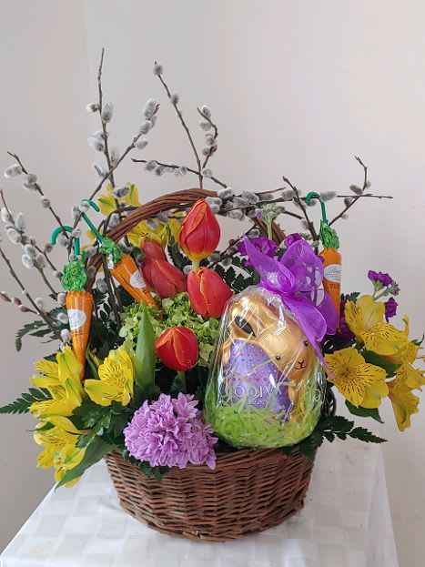 Wicker basket with tulips, yellow alstroemeria, purple blooms and a wrapped chocolate bunny.