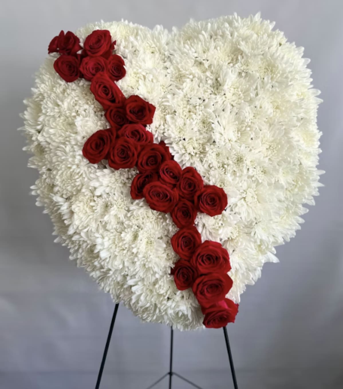 Heart-shaped standing arrangement of white flowers with a diagonal stripe of red roses.