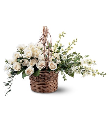 Low wicker basket of cream roses and white flowers in an asymmetrical spray design.
