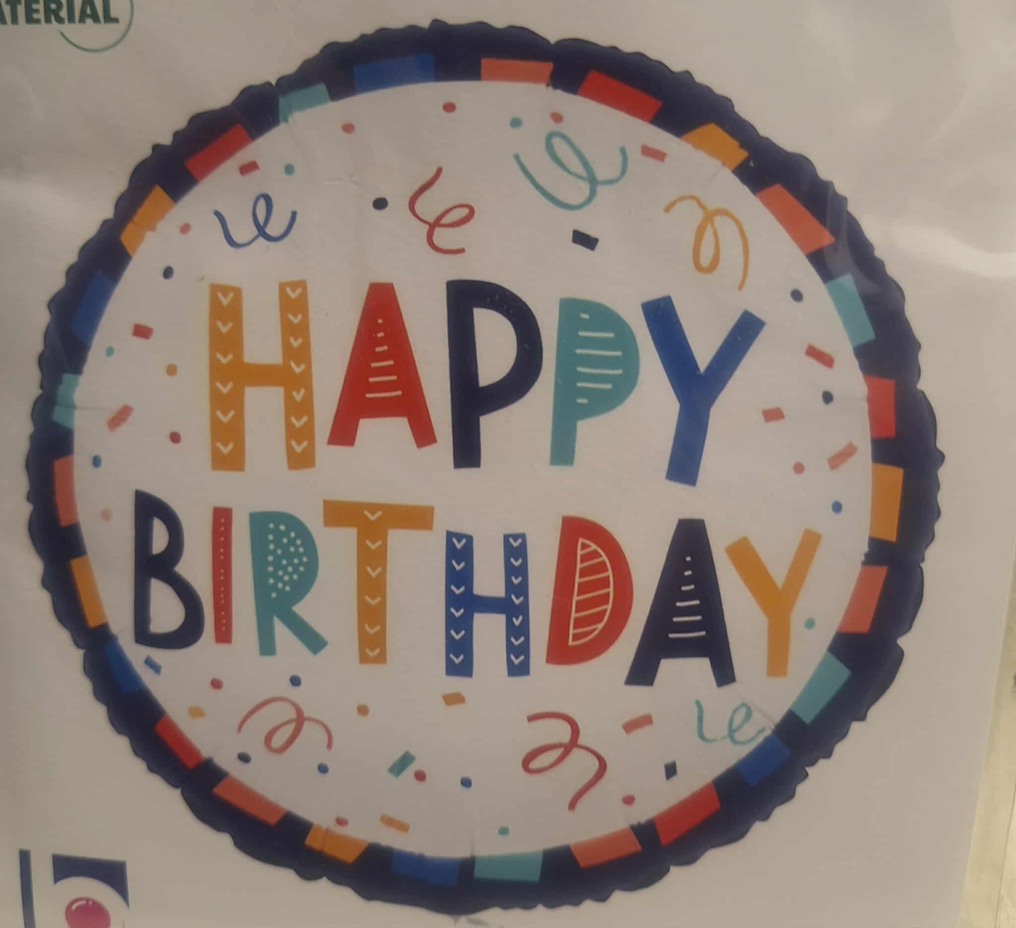 Round foil balloon with colorful Happy Birthday text and confetti accents