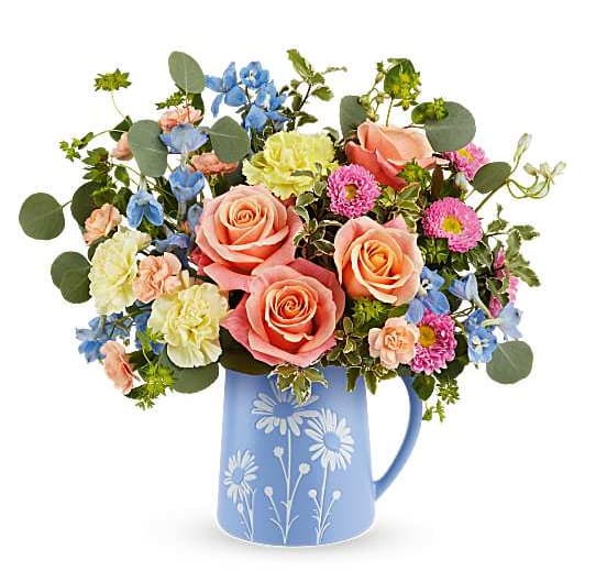 Daisy Dreams Bouquet - Daisy Dreams Bouquet features peach roses, yellow carnations, peach miniature carnations, light blue delphinium, pink Matsumoto asters, bupleurum, silver dollar eucalyptus, and pitta negra, presented in Teleflora's Daisy Dreams Pitcher, a keepsake pitcher with a playful daisy design. Orientation: All-Around  SUBSTITUTION POLICY – Always deliver the freshest flowers! Please note the bouquet pictured reflects our original design.  If the exact flowers or container in this arrangement are not available, our local florists will create a beautiful bouquet with the freshest available flowers.