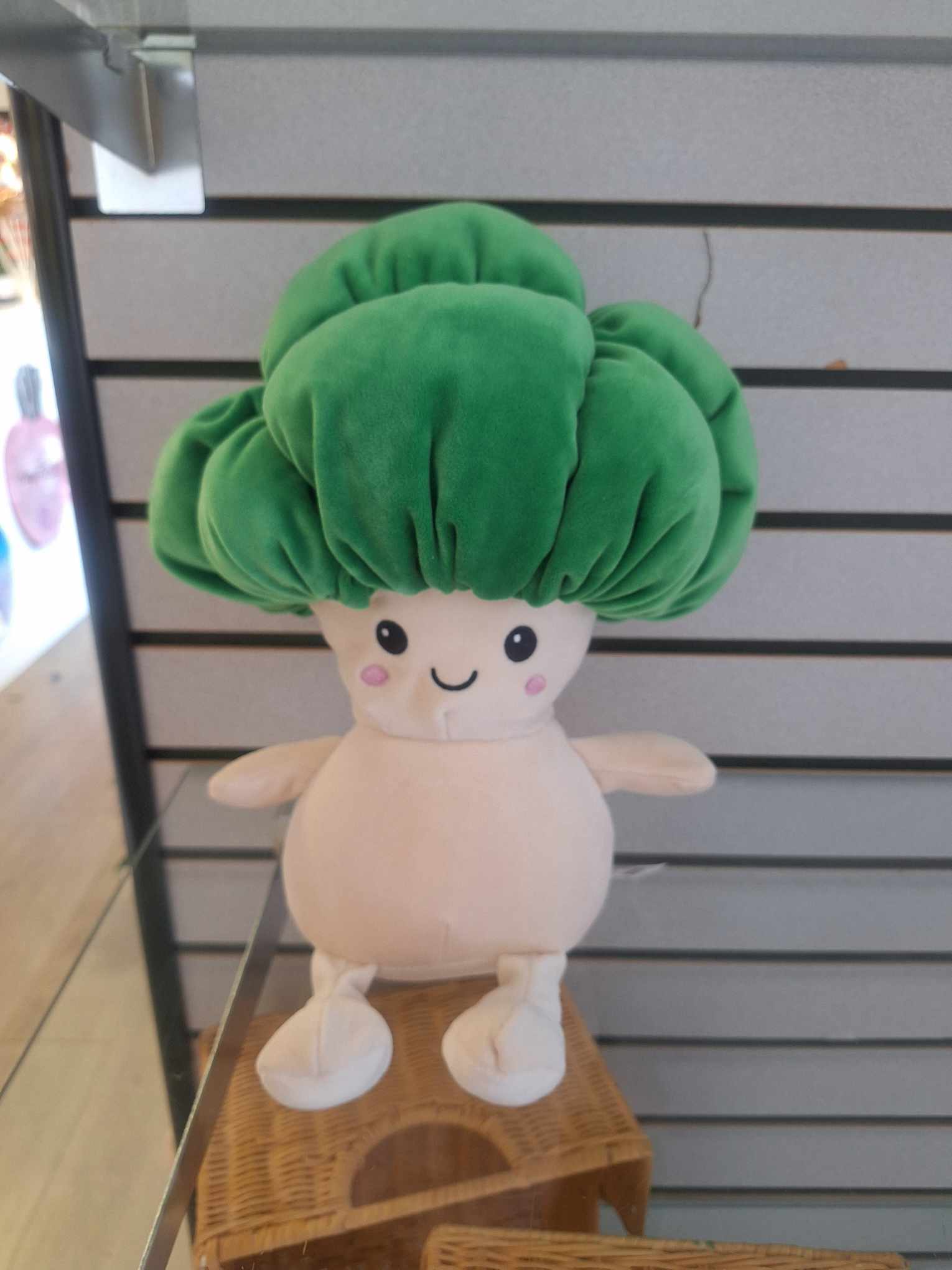 Plush toy with a large green top and cream body displayed on a shelf