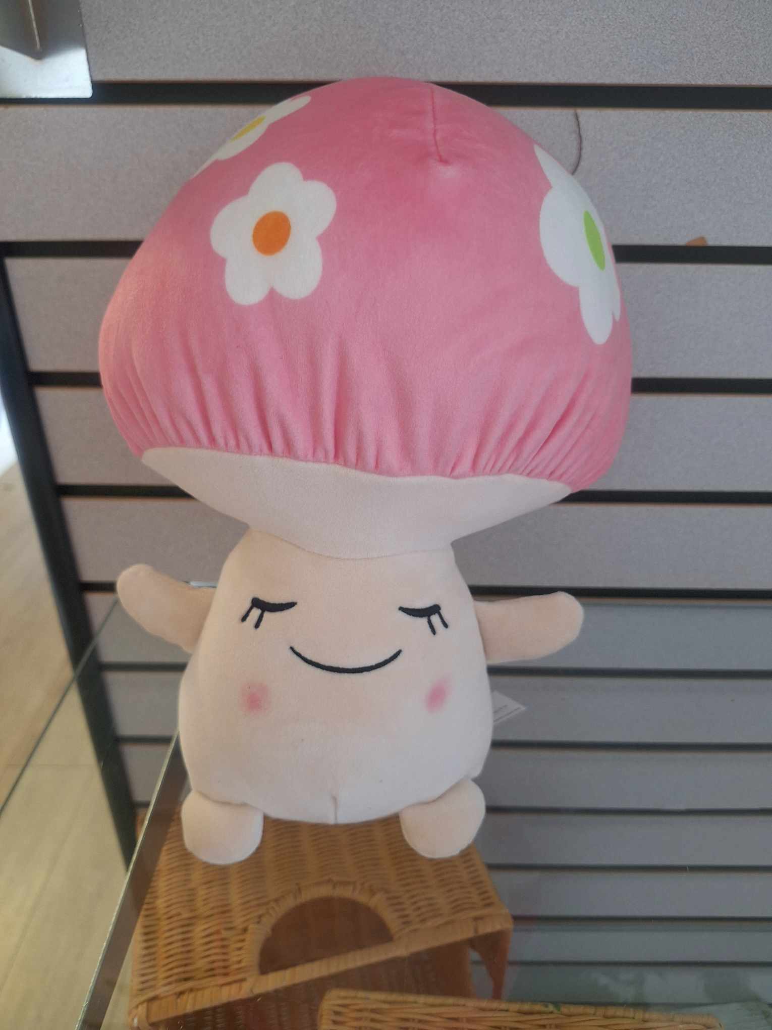 Plush pink-capped mushroom toy with a smiling face and flower spots on top.