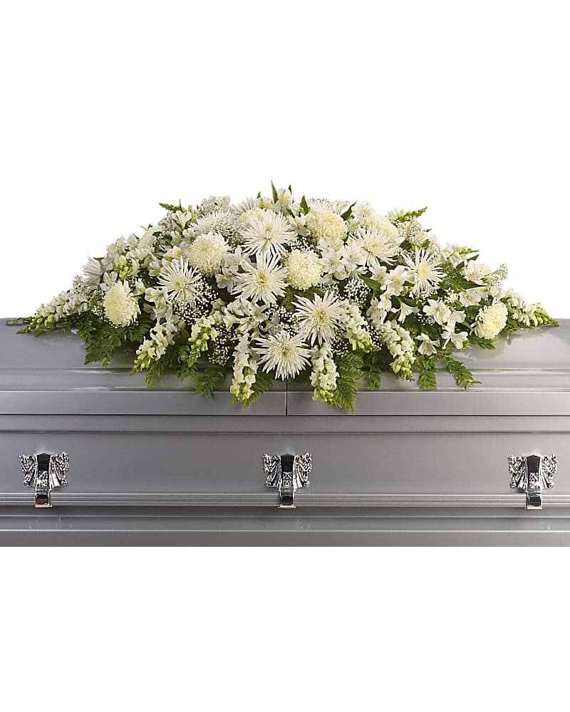 White casket spray of chrysanthemums and mixed white flowers on a silver casket.