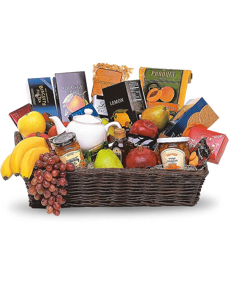 Large wicker gift basket filled with assorted fruits, snacks, and a white teapot