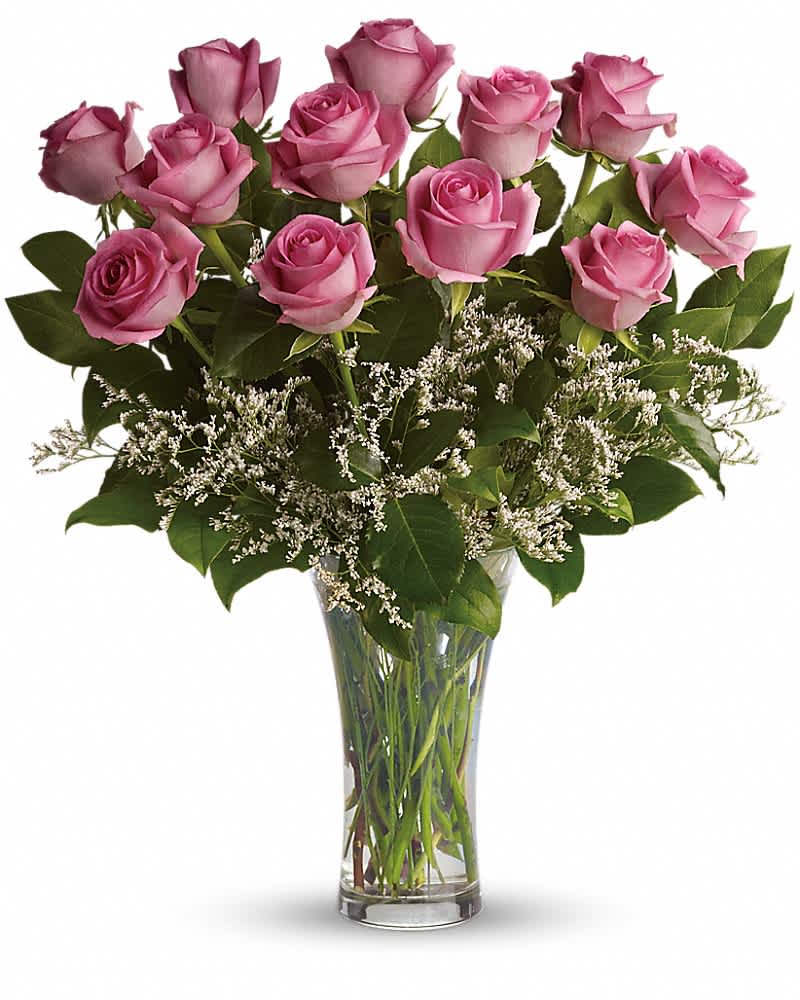 Tall clear vase of pink roses with delicate white filler flowers