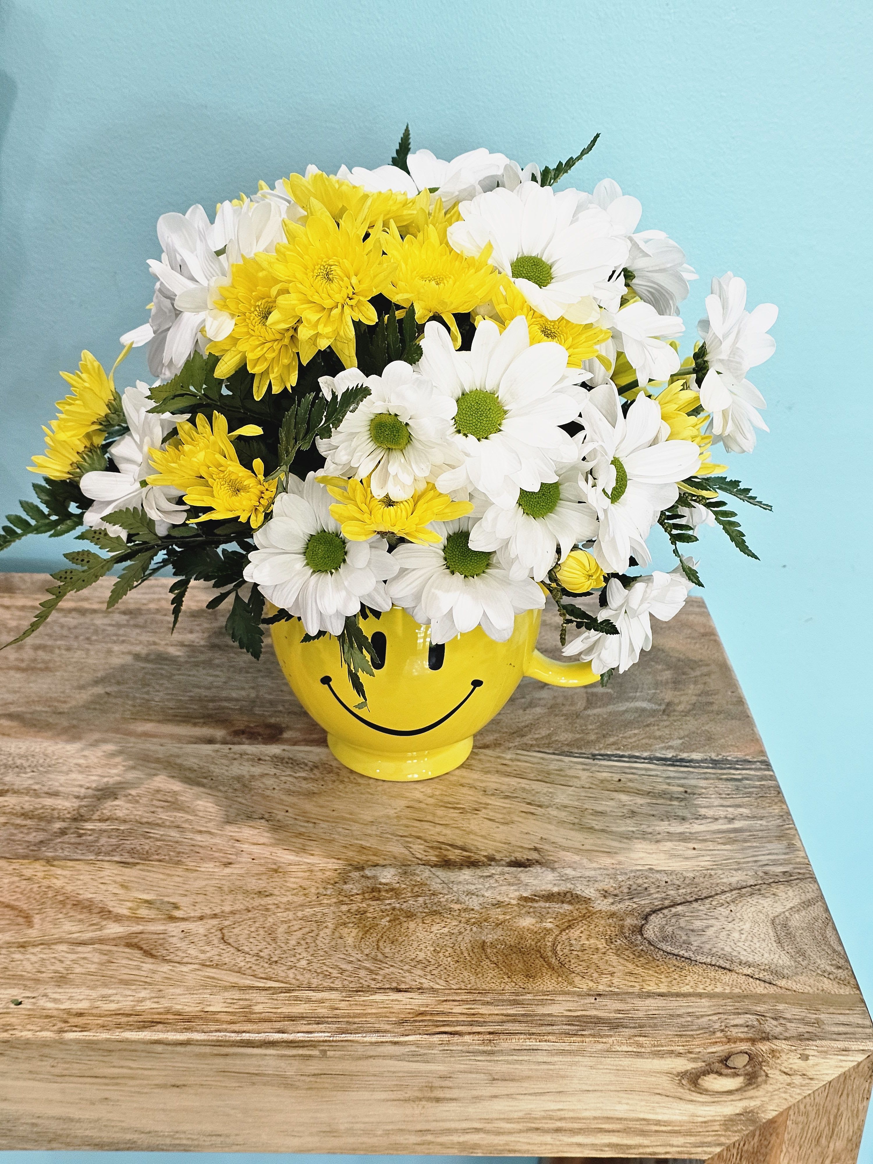 Sunny sunrise - Experience the warmth and brightness of a sunny sunrise with our Yellow and White Daysis arrangement. The fine filler and greenery add an elegant touch to the yellow smile face ceramic vase. Bring a ray of sunshine into your space with this beautiful and cheerful piece.